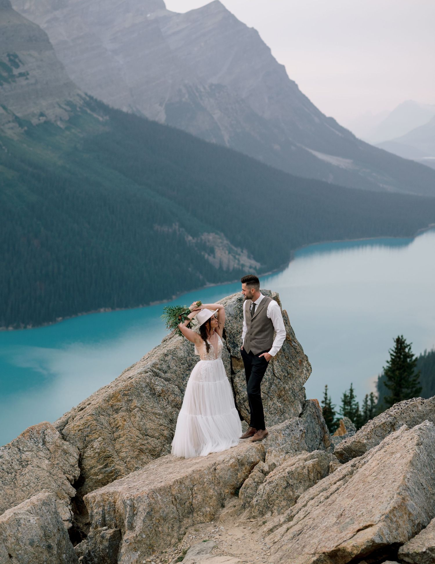 Couple shares a romantic moment on a rocky overlook above the turquoise waters of Peyto Lake in Banff National Park.