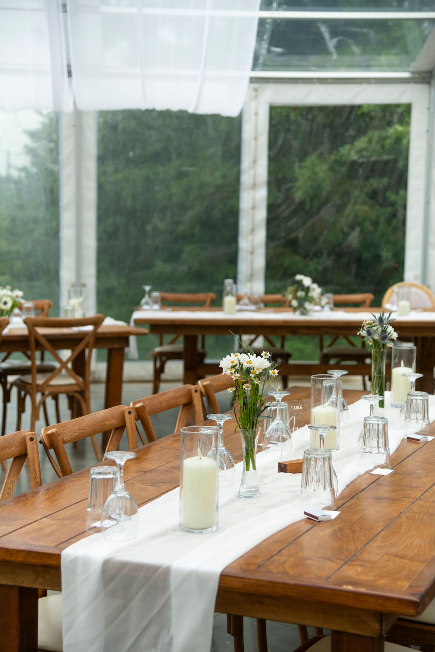 Elegant wedding reception tables set under clear tent with white table runners and simple floral centerpieces. Calgary Wedding Photographer