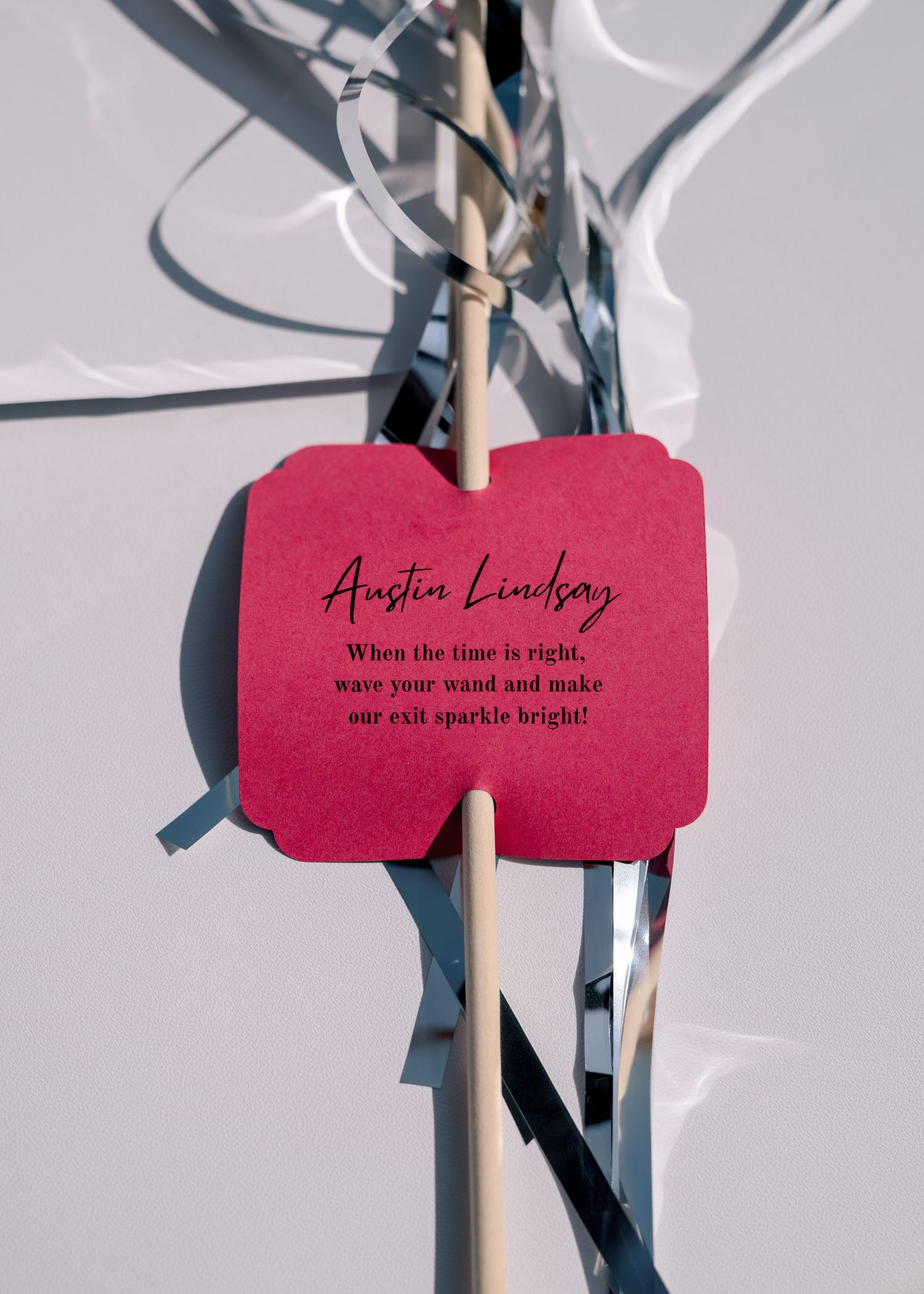 A red paper label with handwriting is clipped to a metal stand against a white background.