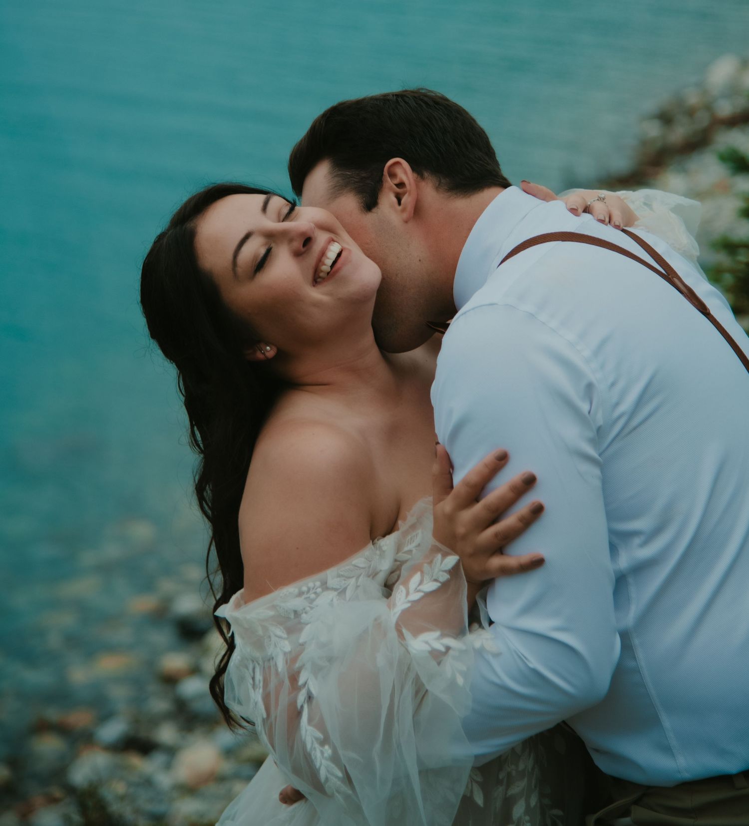 An intimate moment between newlyweds with turquoise water in the background.