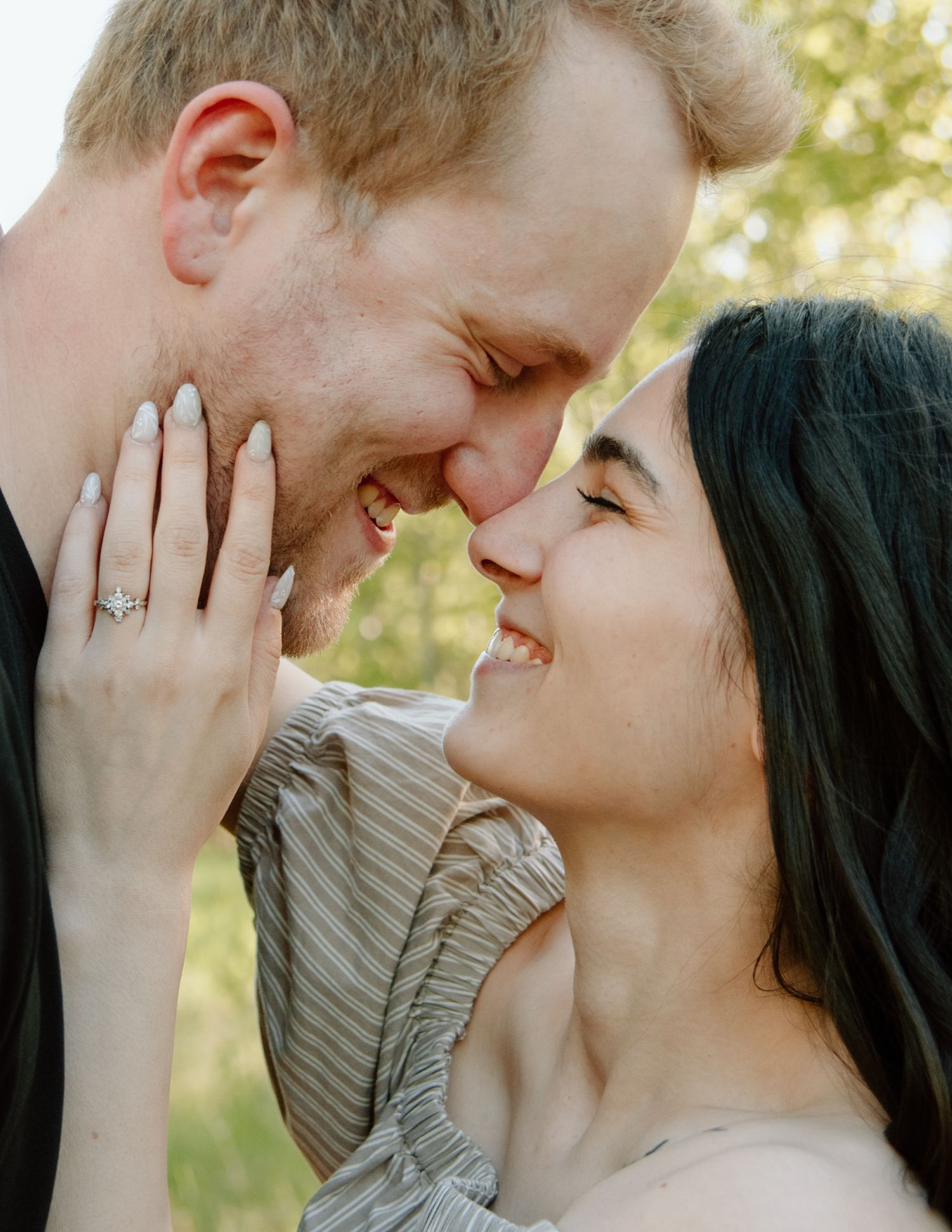 Tender candid moment between couple sharing laughter and affection outdoors. Calgary Alberta Engagement Photographer