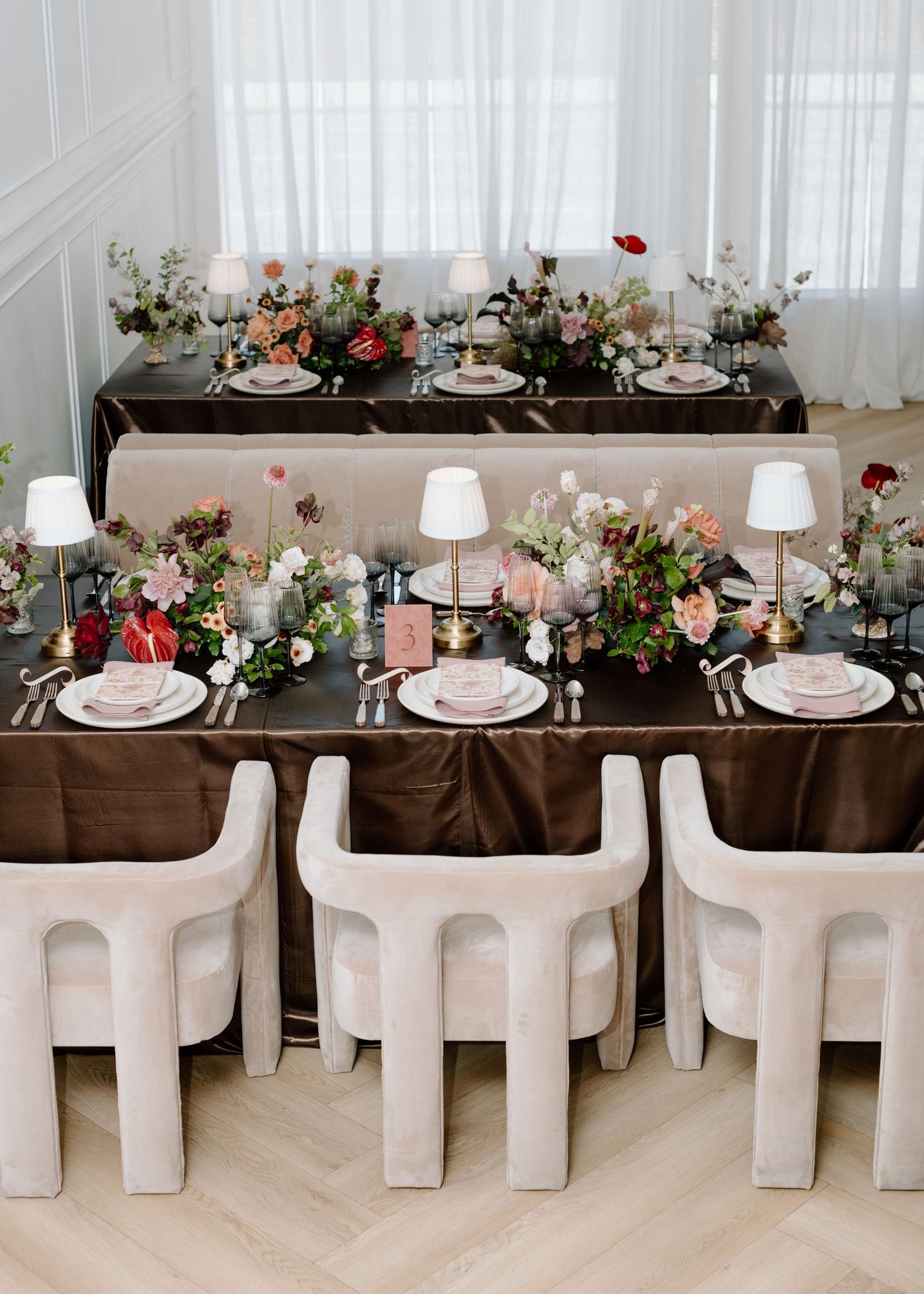 Elegant table setting with brown linens, white chairs, and beautiful floral centerpieces featuring pink and red blooms at the Studio at Vic