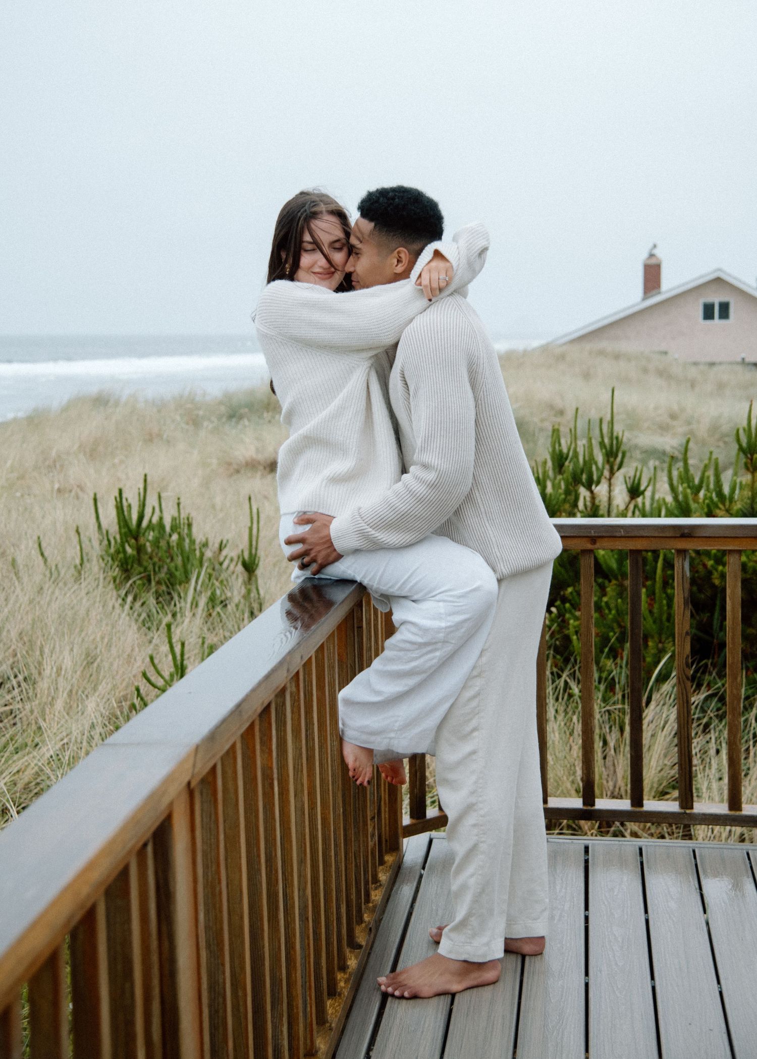 Three photos show a romantic moment between a couple in white robes standing on a wooden deck overlooking coastal grasses.