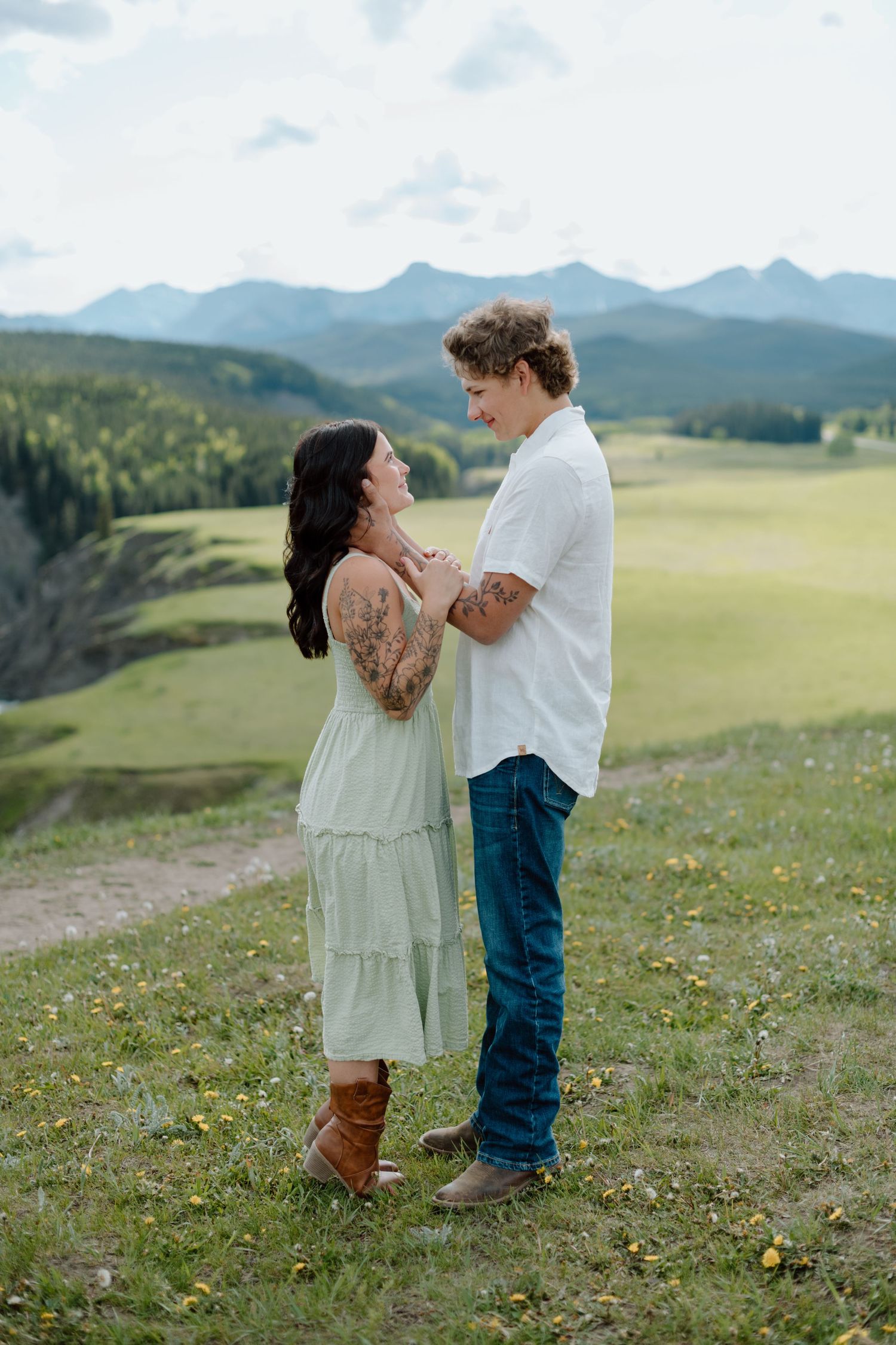 A tender moment shared between two people on a hillside with mountain views in Calgary, Alberta Calgary Lifestyle and Engagement Photograph