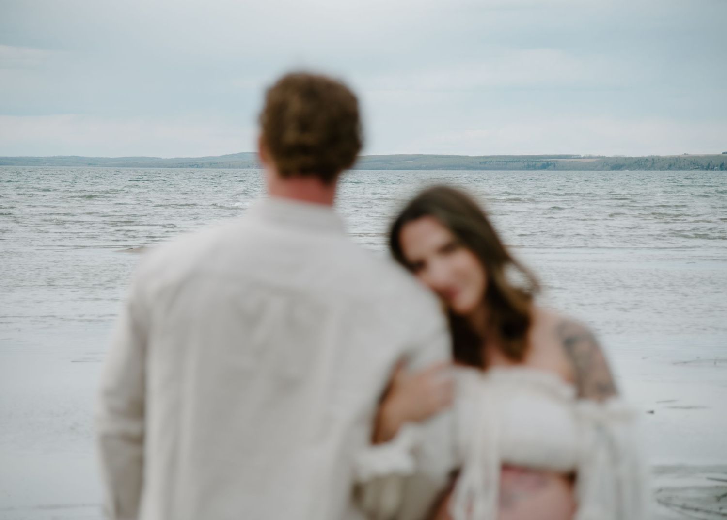 Artistic maternity photo on a beach with soft focus and dreamy atmosphere. Calgary Alberta Maternity Photographer.