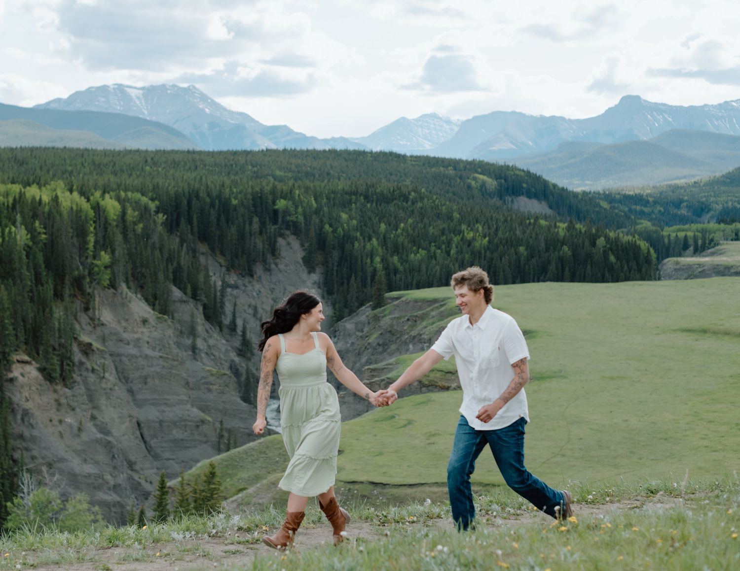 A couple exploring a scenic mountain overlook with vast forest views and dramatic cliffs in Calgary, Alberta Calgary Lifestyle Photographer