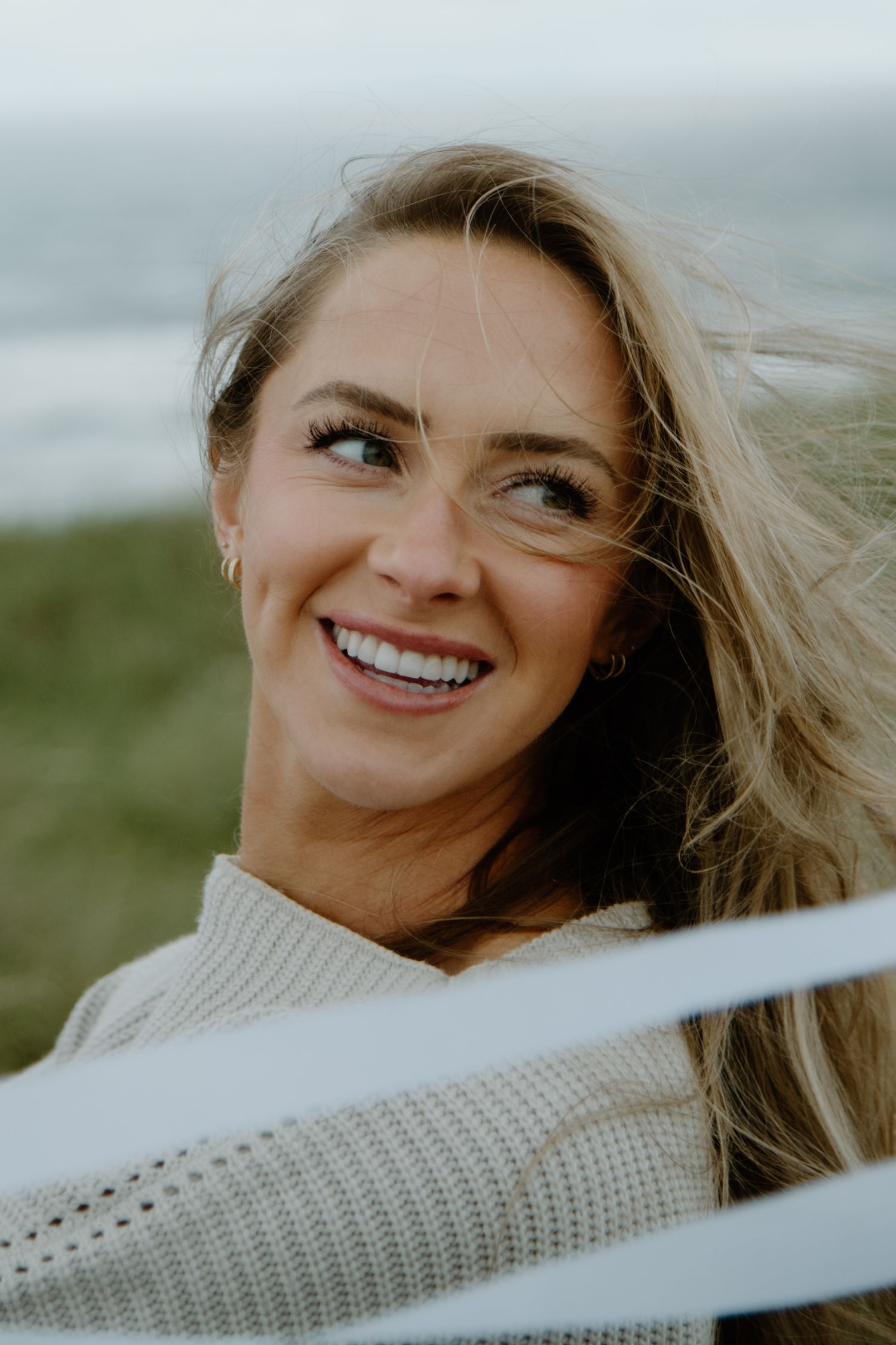 Close-up portrait showcasing genuine joy and laughter against a blurred coastal background on Oregon Coast. Calgary Lifestyle and Engagement