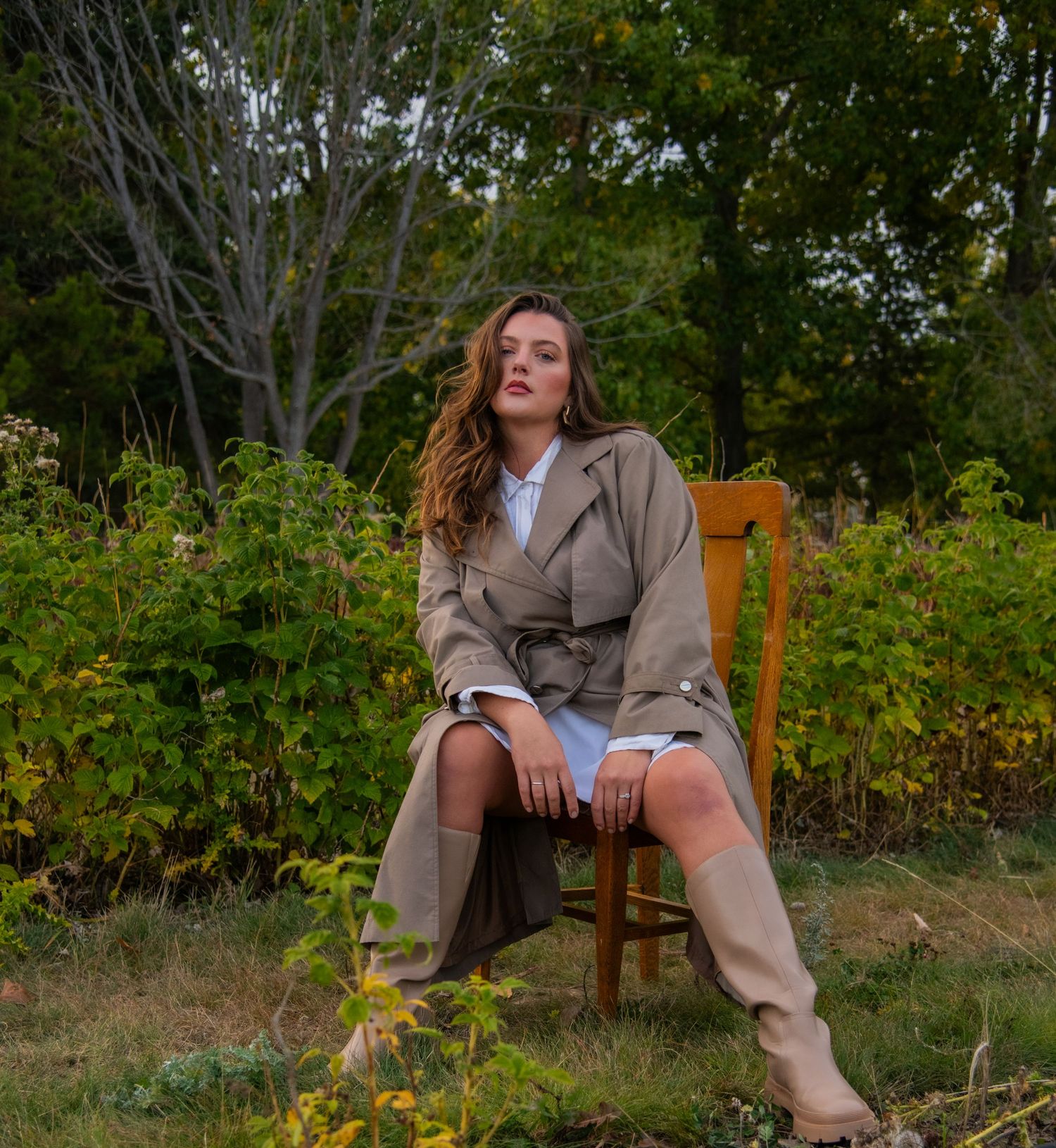 Autumn fashion portrait on wooden chair surrounded by garden foliage. Calgary Alberta Branding Photographer.