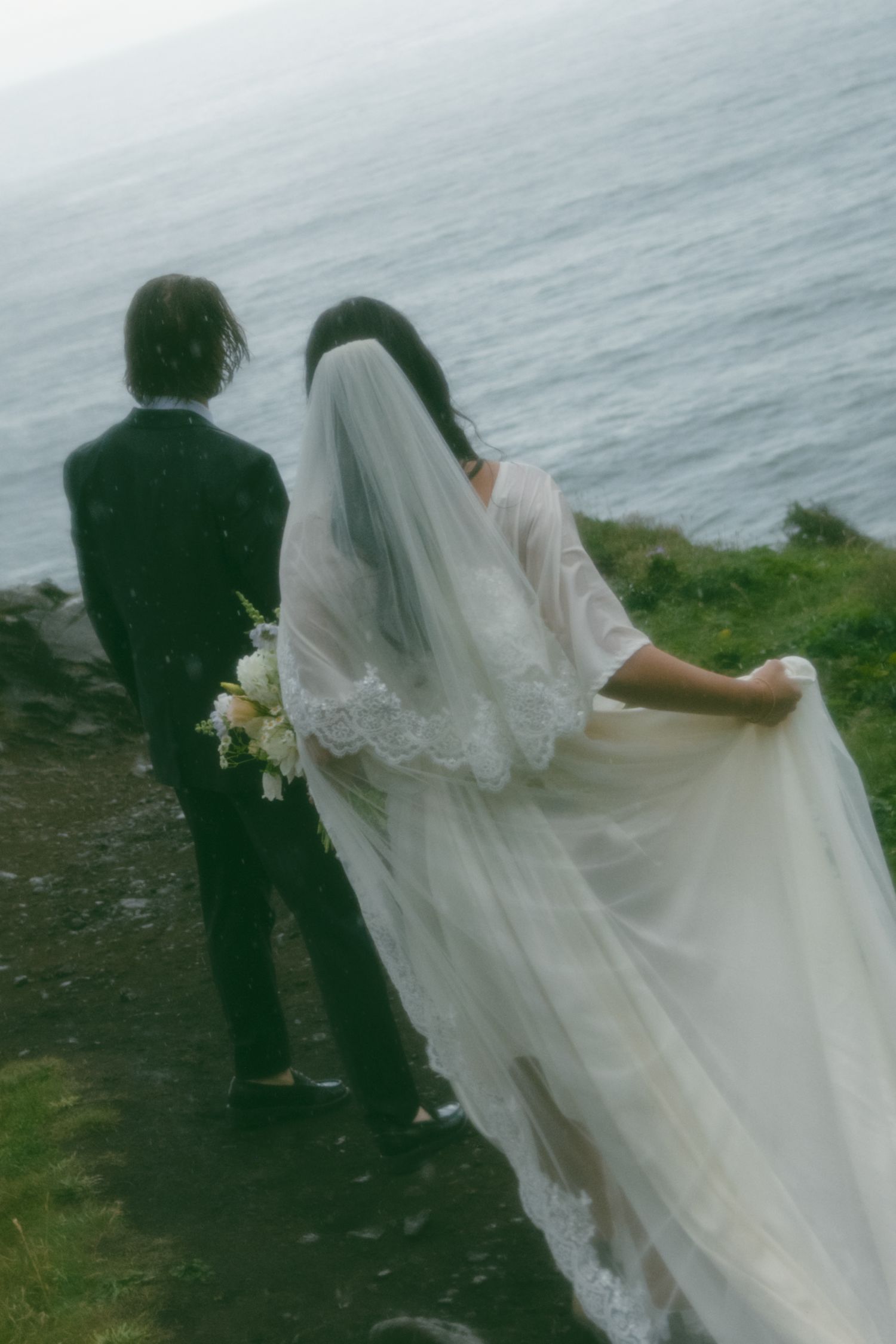 A dreamy, soft-focus shot of a couple overlooking the ocean from a cliff edge. Calgary Wedding Photographer