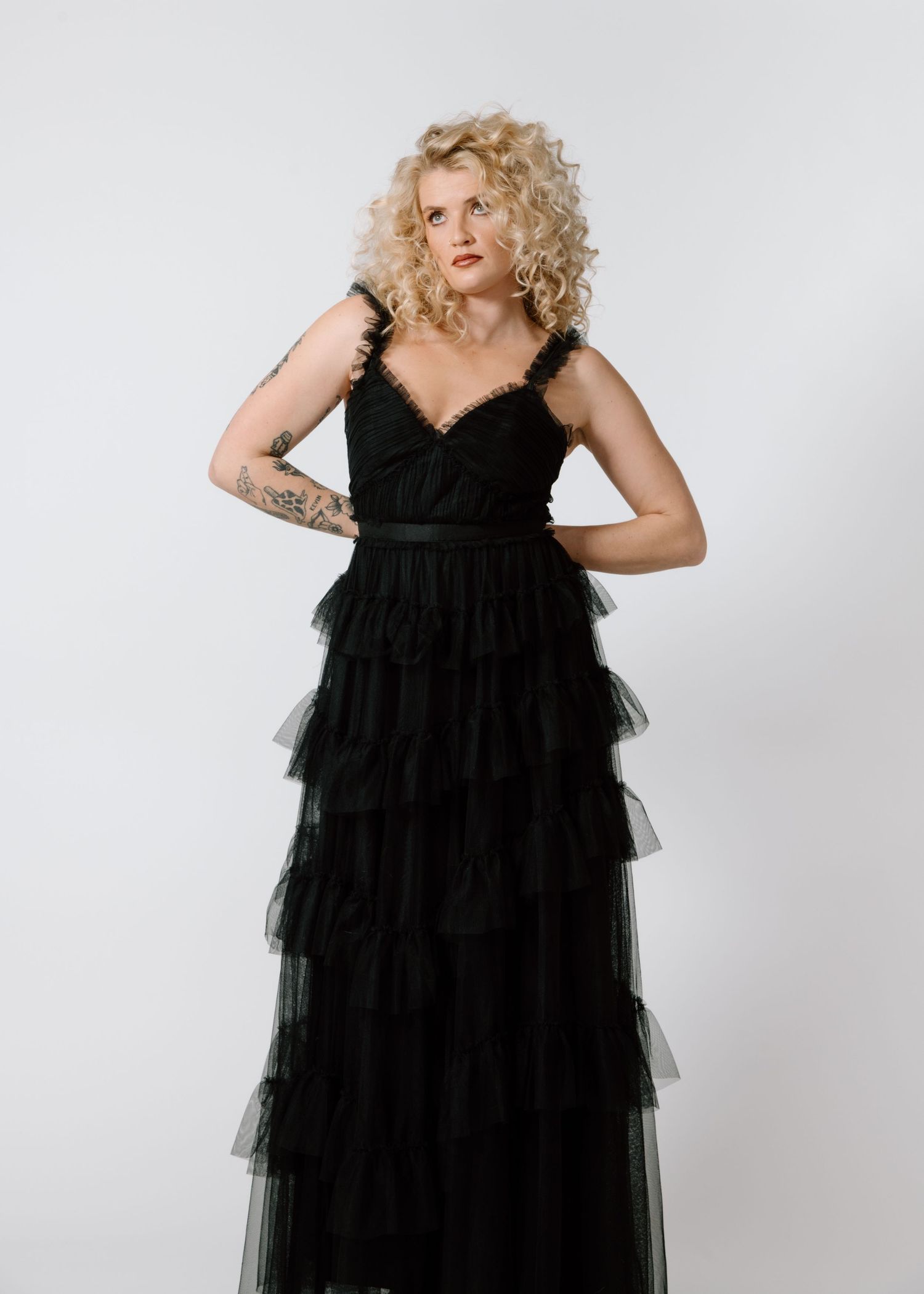 Model in black tulle tiered evening gown poses against white backdrop. Calgary Alberta Branding Photographer.