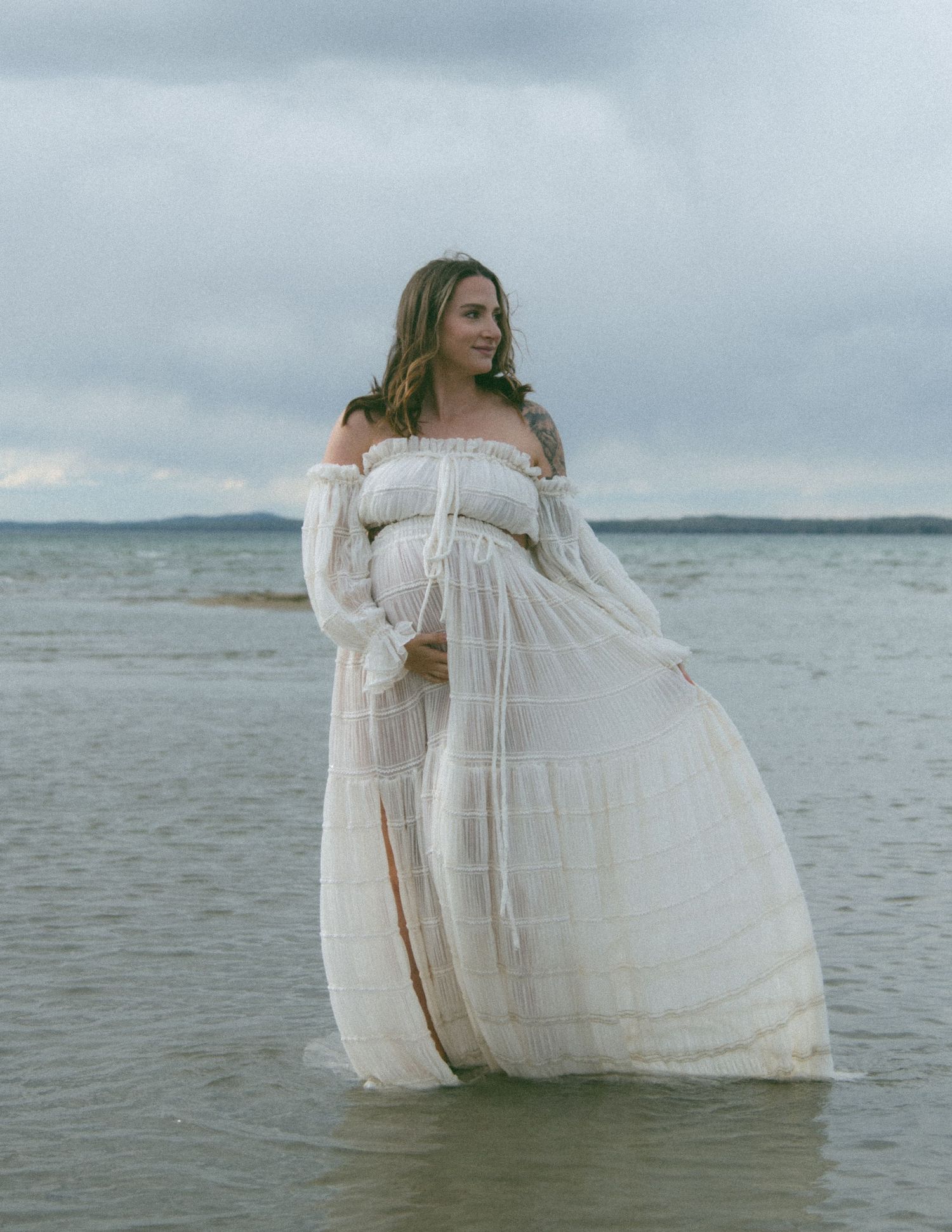 Dreamy beachside portrait with white lace dress reflecting in calm waters. Calgary Alberta Maternity Photographer.