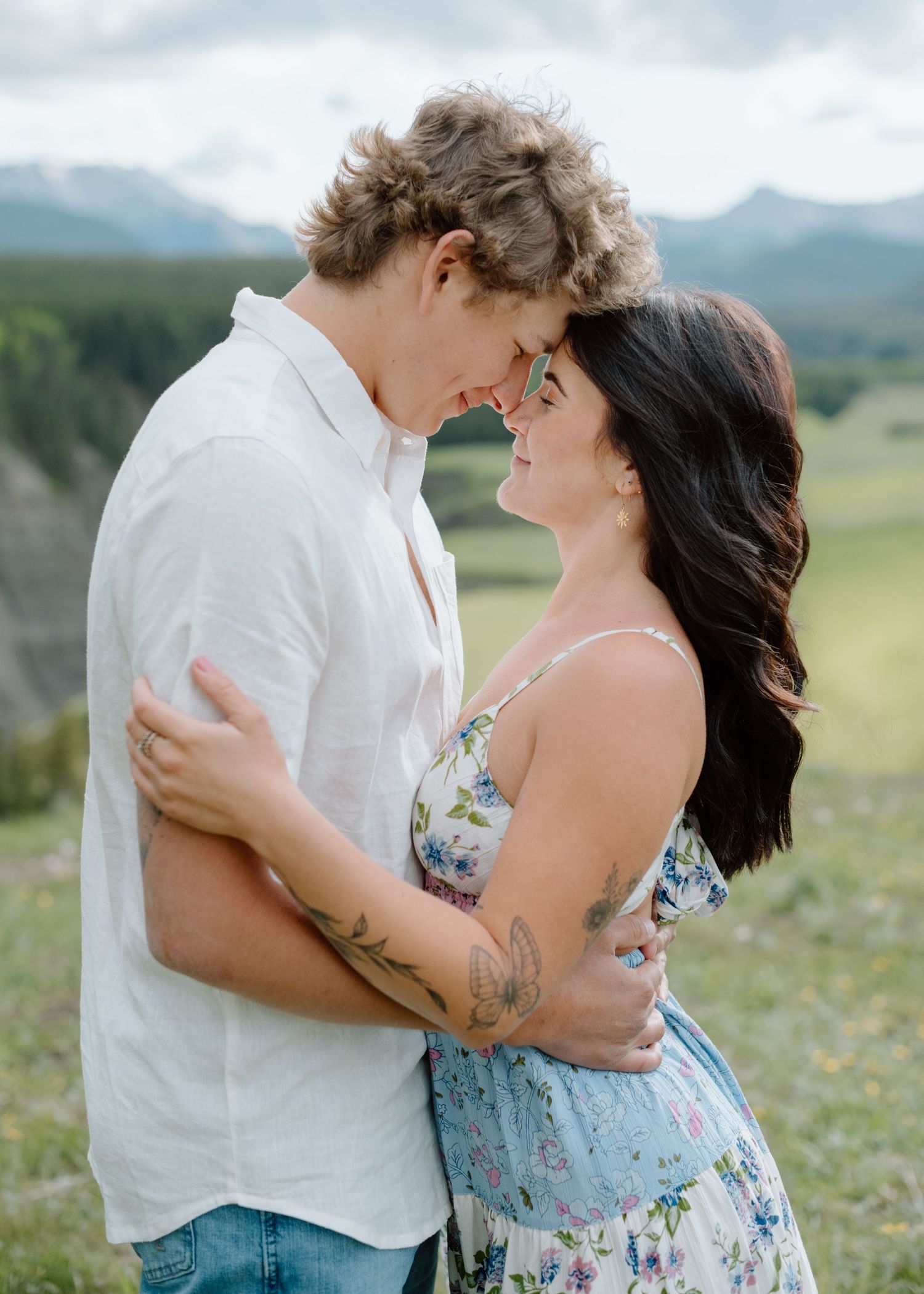 An intimate portrait of a couple embracing in a mountain meadow with scenic views. Calgary Alberta Engagement Photographer.