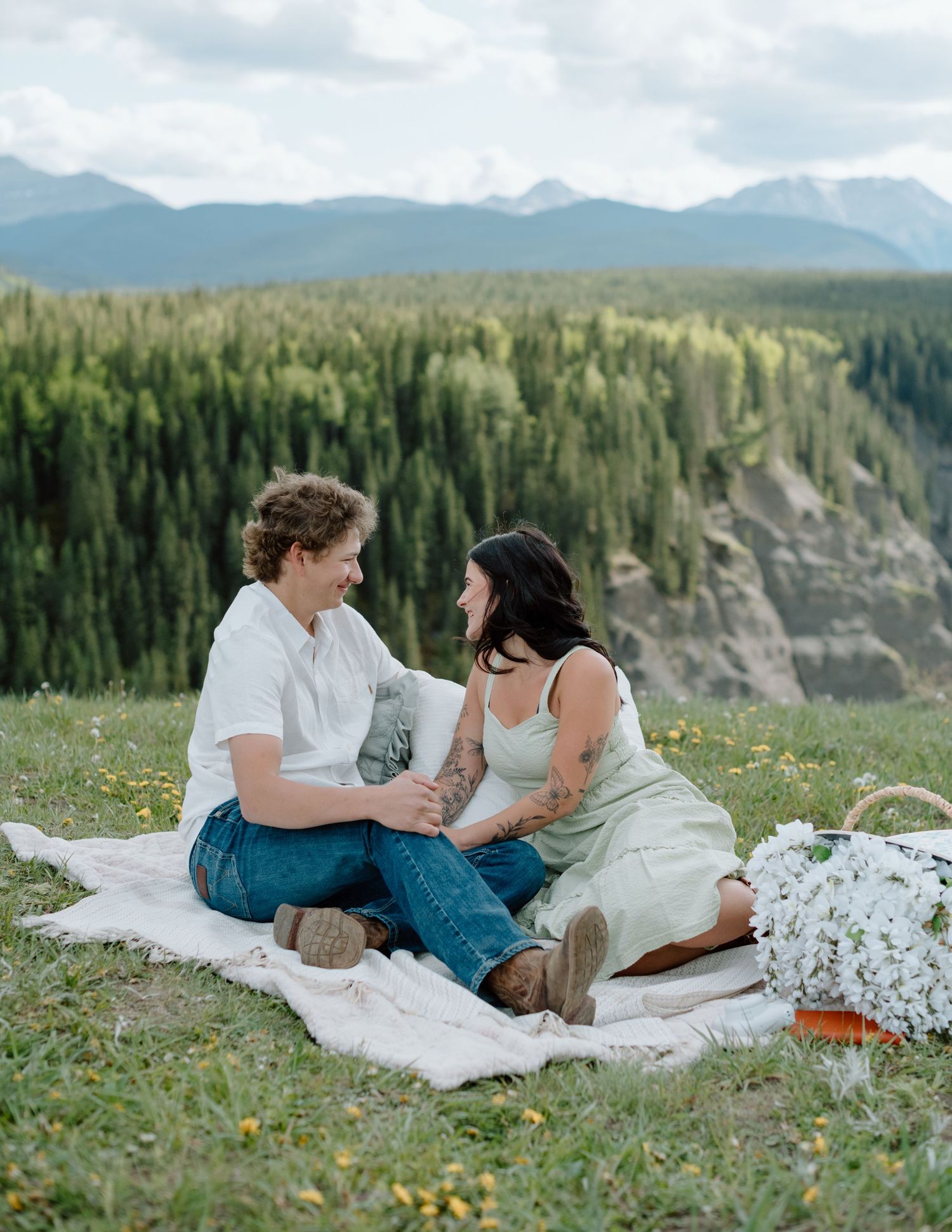 A sweet moment shared during a mountaintop picnic with sweeping valley views. Calgary Alberta Engagement Photographer.