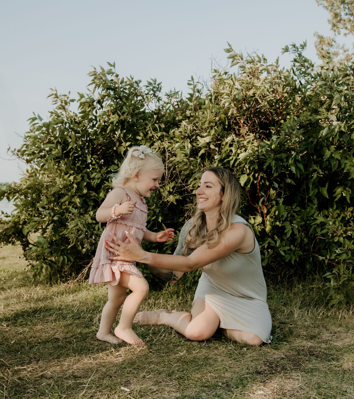 A playful moment captured between parent and child against a leafy green background. Calgary Alberta Family Photographer.