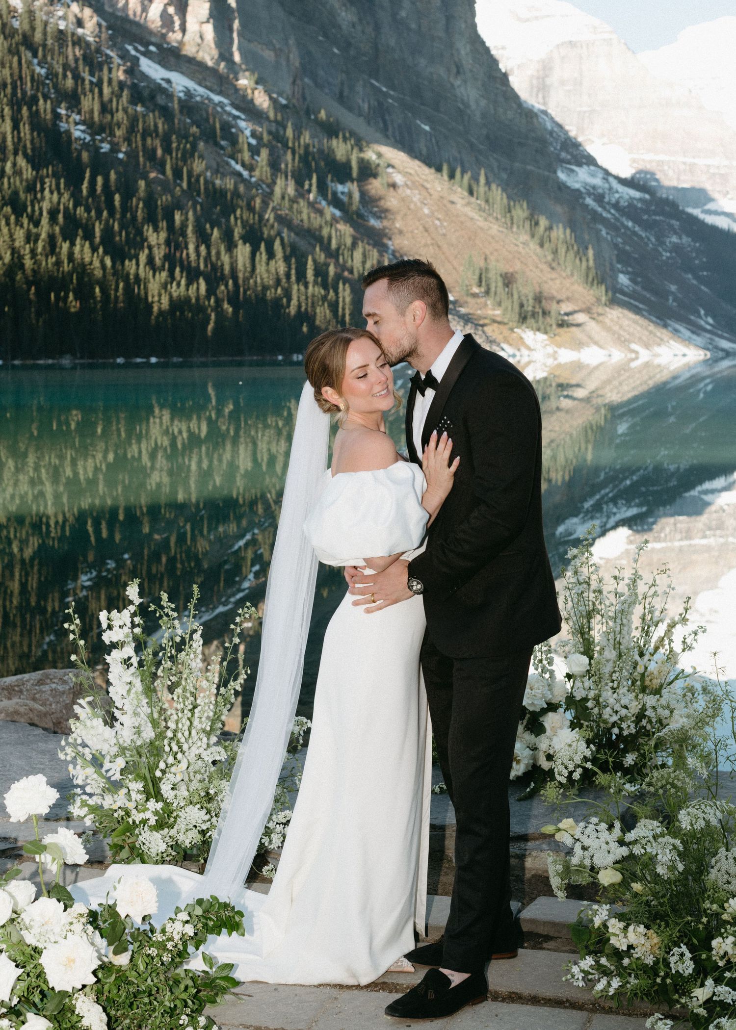 Romantic wedding ceremony by Lake Louise in Banff National Park with towering mountains and turquoise waters as backdrop.