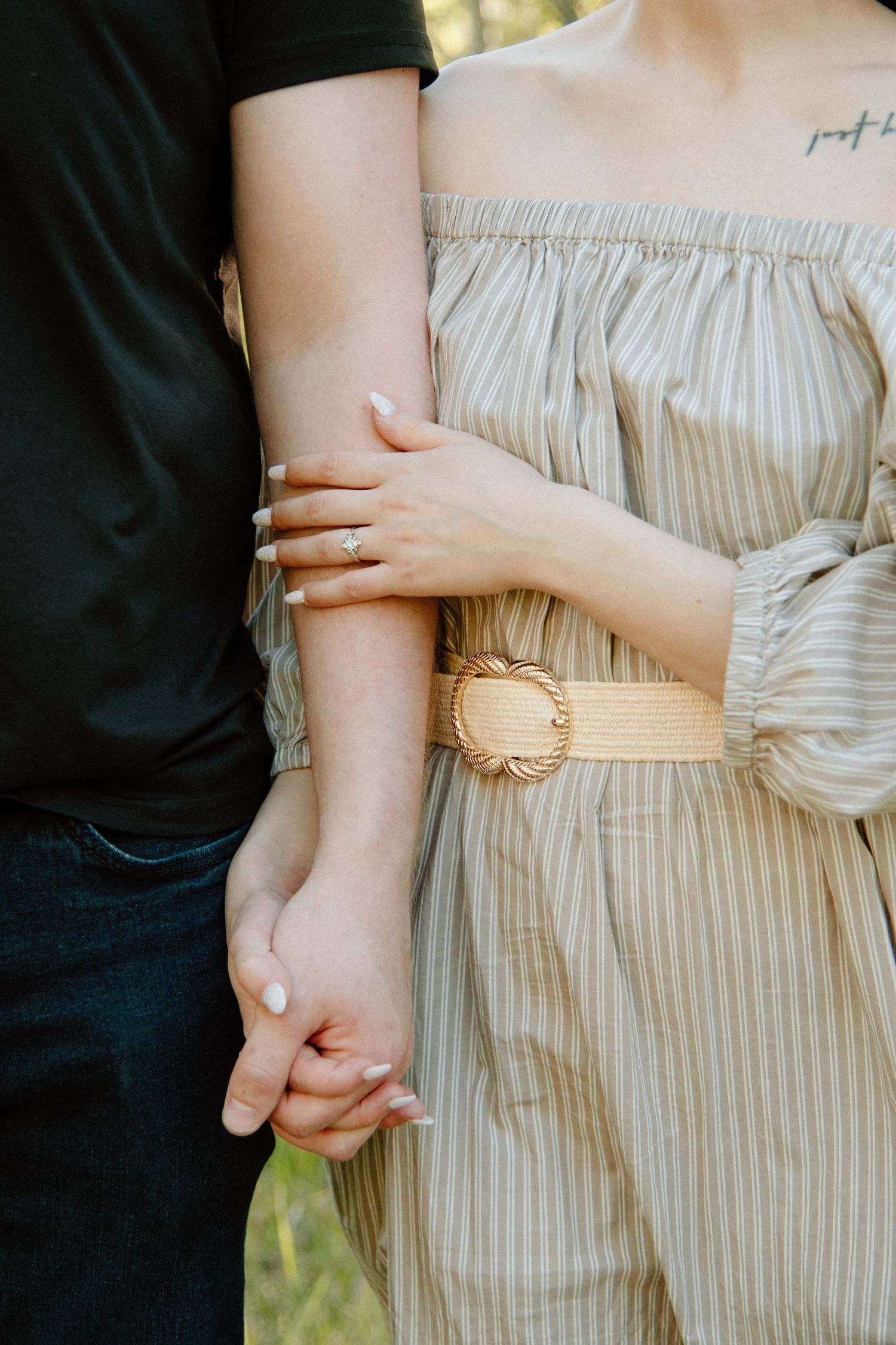 Close-up details of striped outfit with tan belt and gentle embrace. Calgary Alberta Engagement Photographer