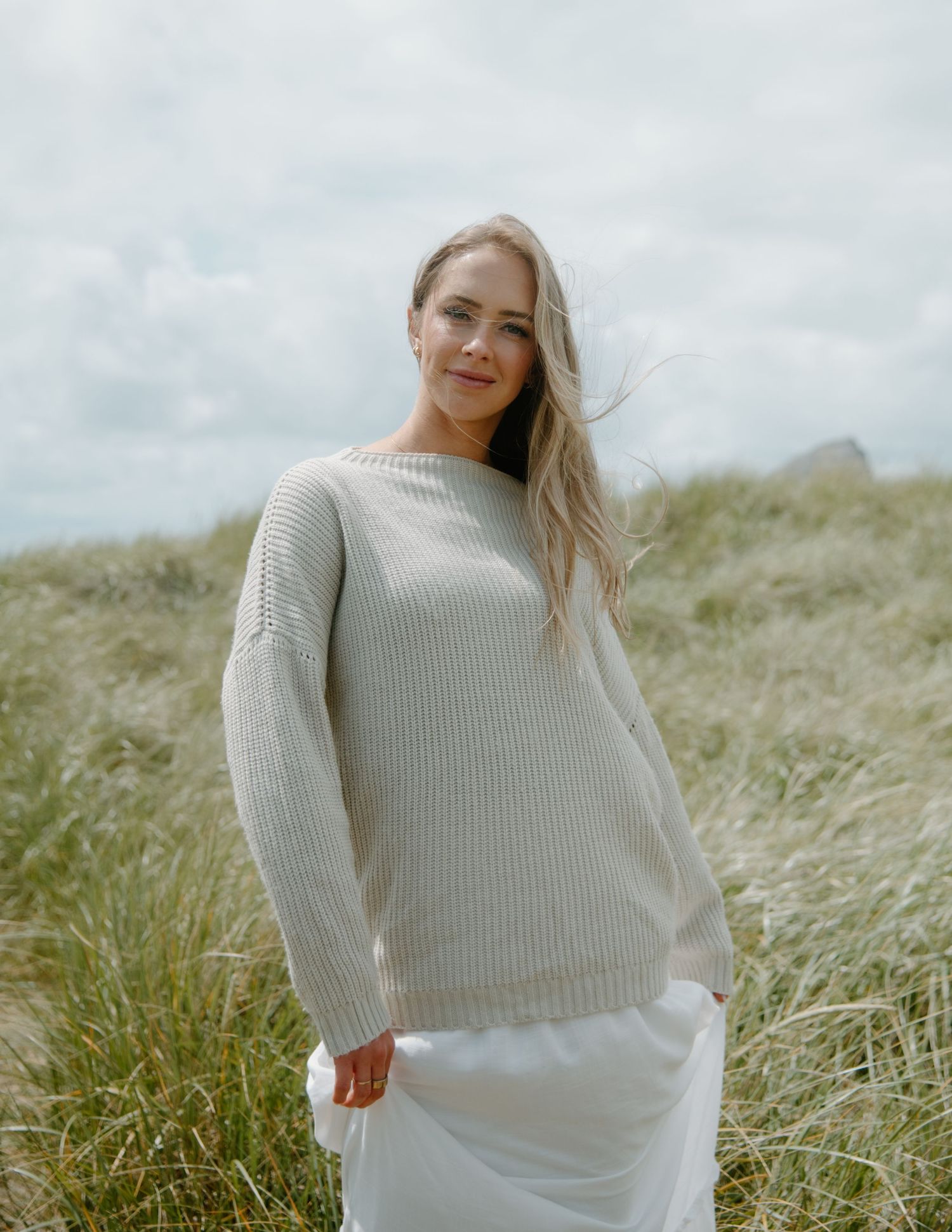 Casual lifestyle portrait showing someone in white attire standing among windswept coastal grasses on Oregon Coast. Calgary Lifestyle.