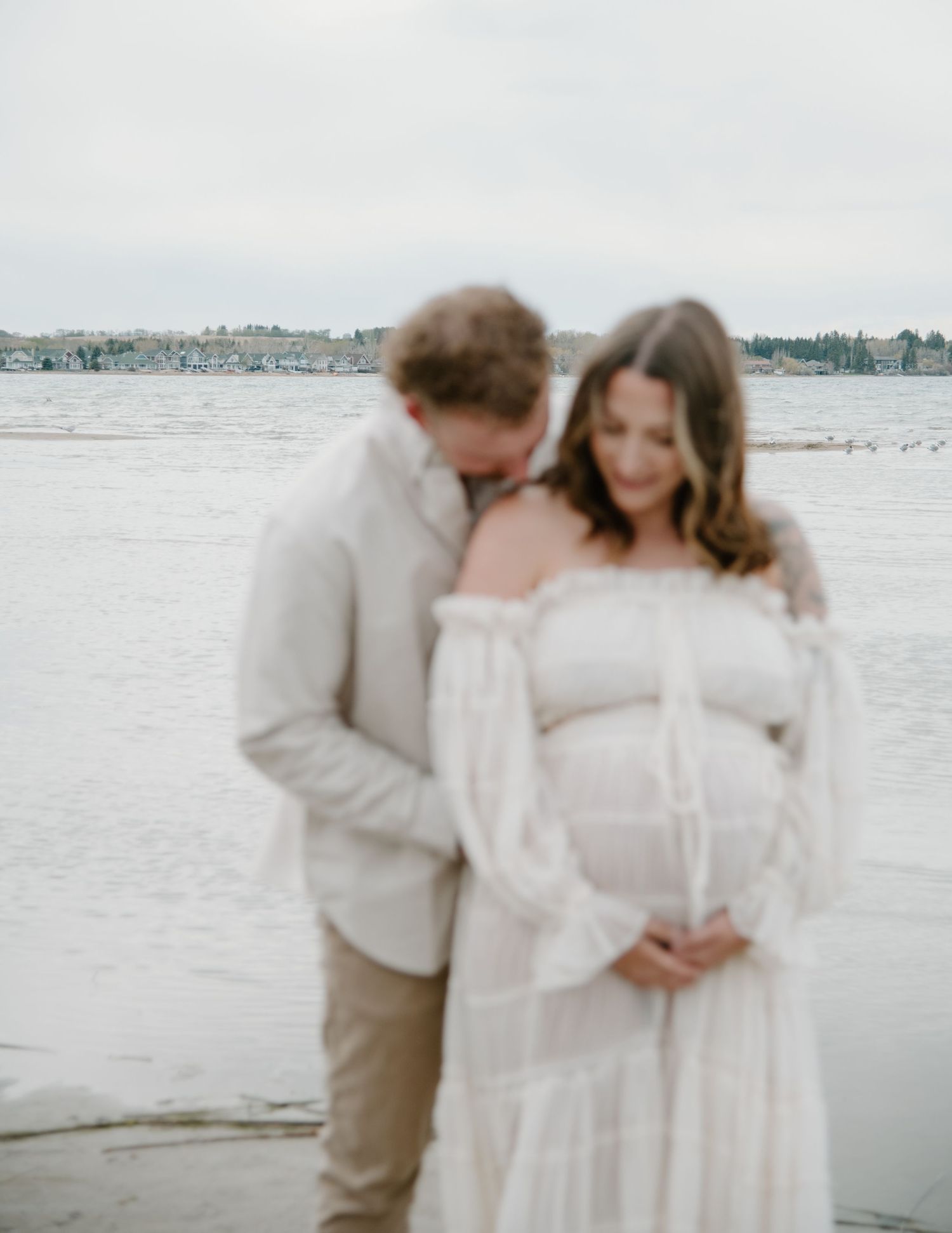 Soft, romantic beach maternity session featuring gentle embraces and flowing white dress. Calgary Alberta Maternity Photographer.