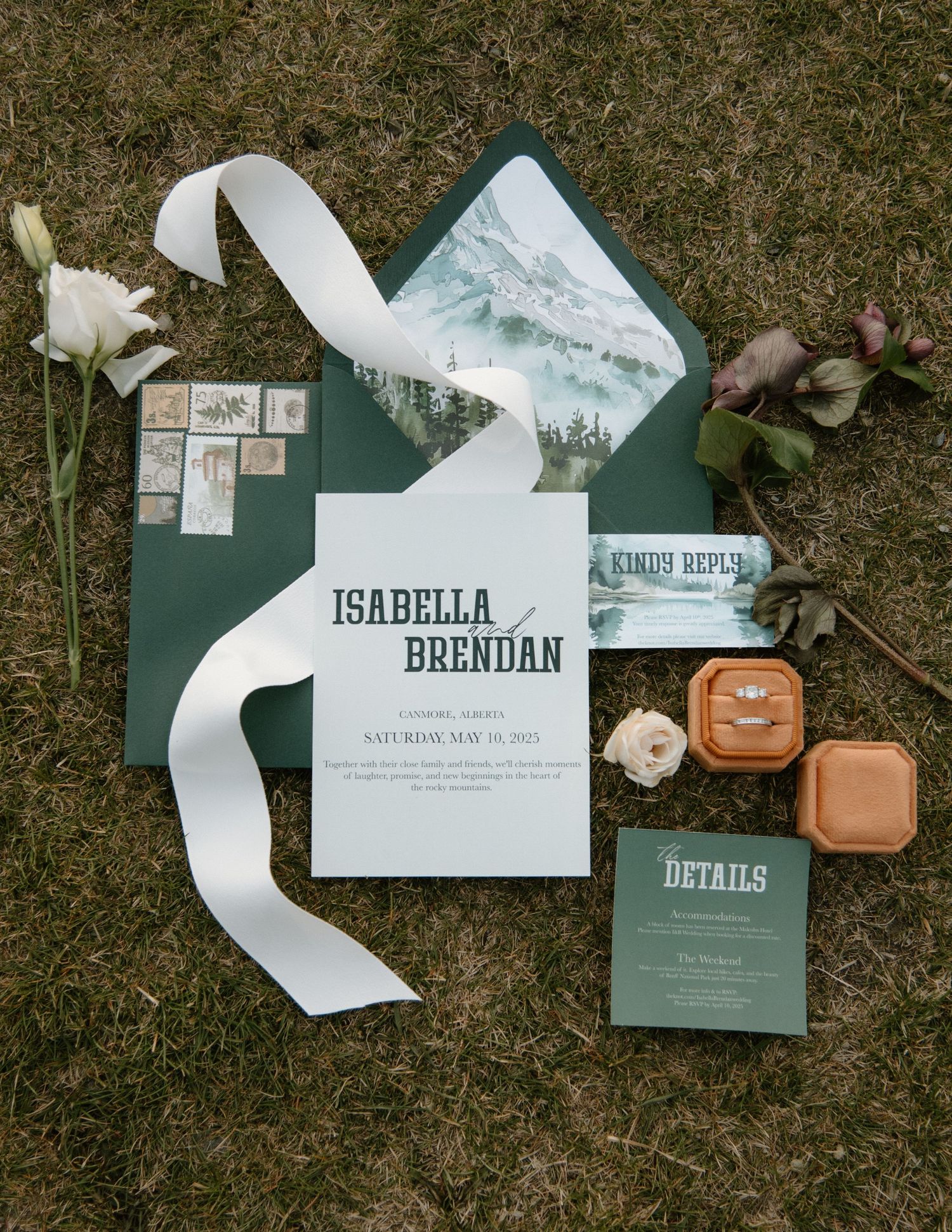 Wedding invitation suite in teal green with white ribbon and floral details laid on grass. Calgary Wedding Photographer