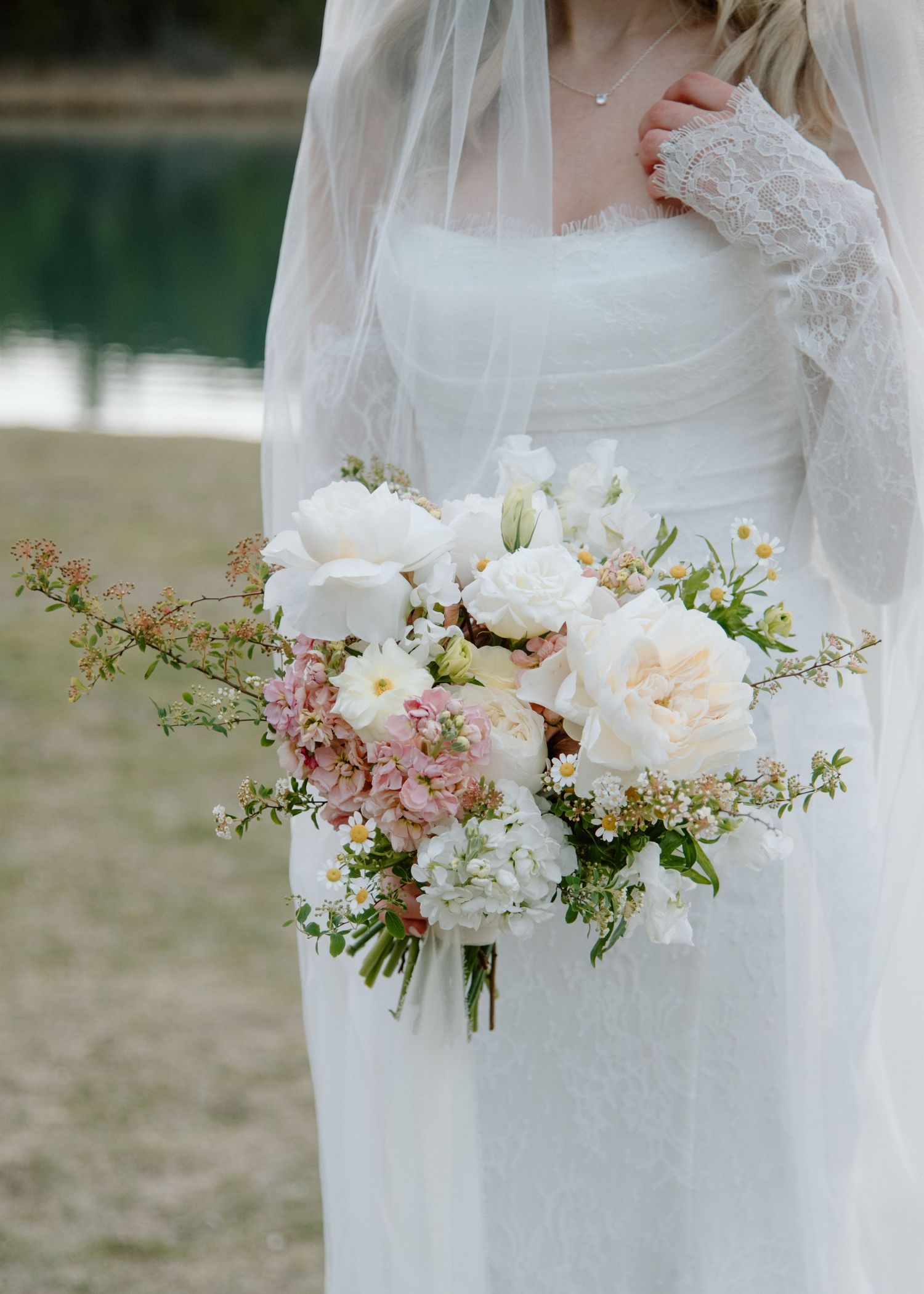 Romantic bridal bouquet with white and pink flowers against scenic lakeside background. Banff and Calgary Wedding Photographer