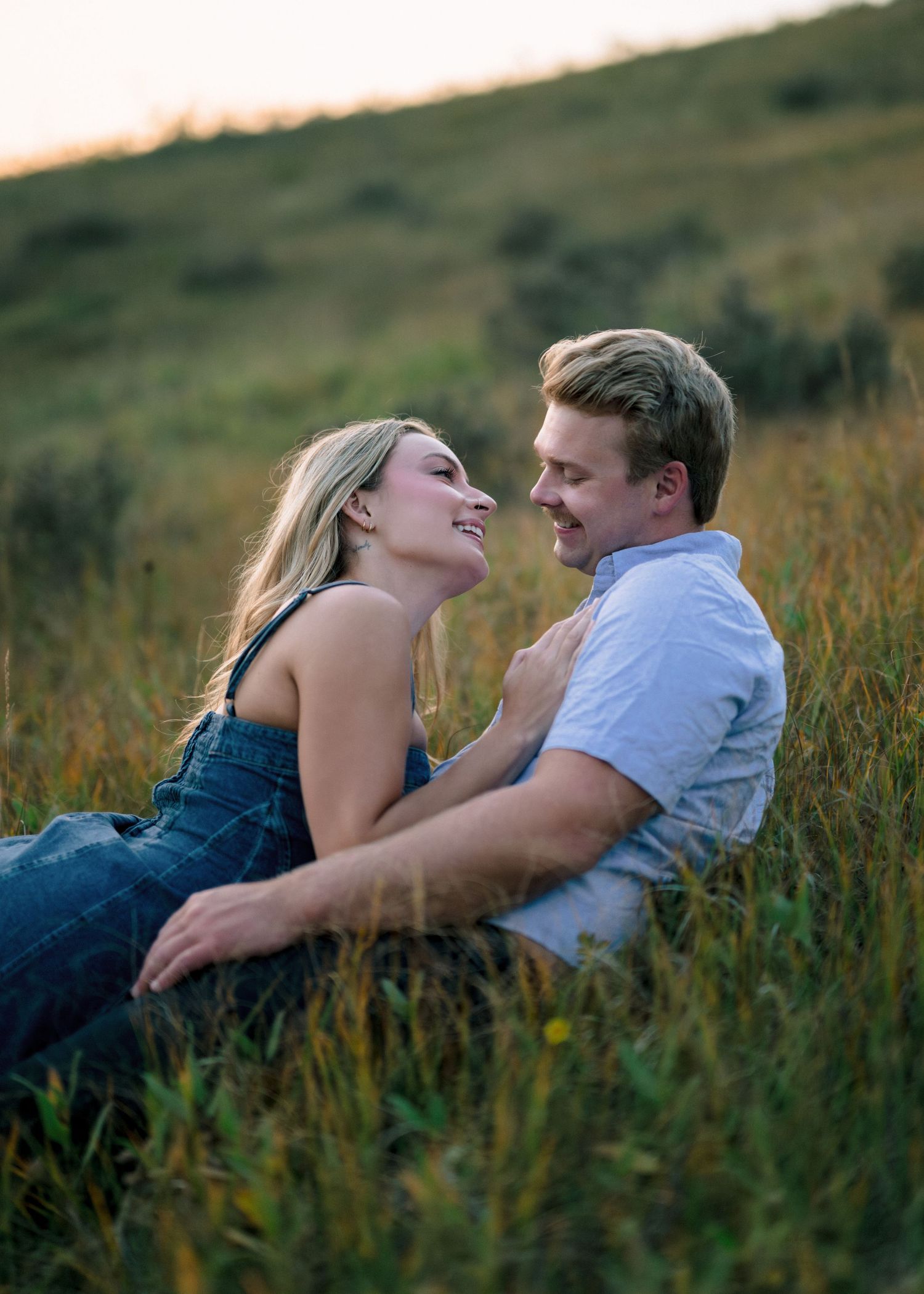 A couple laying together in a grassy meadow during golden hour, sharing romantic moments in sequence.
