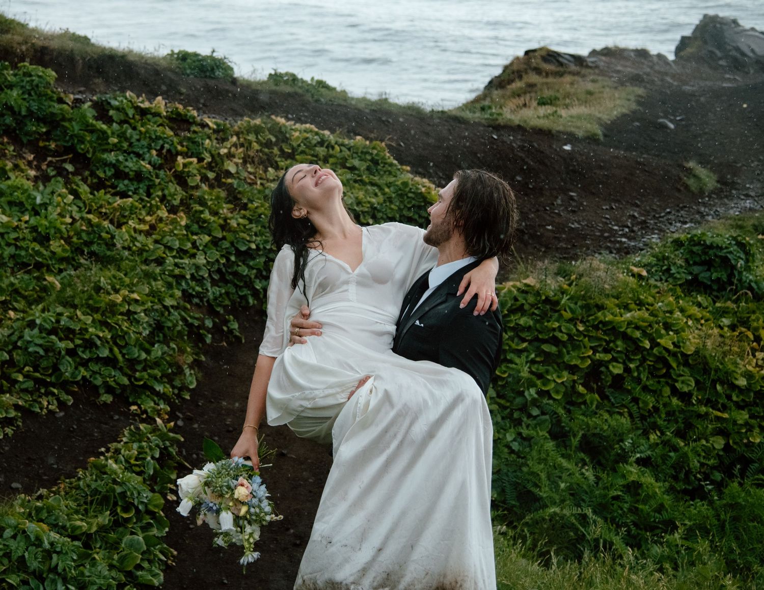 Wedding couple embracing on coastal cliffs with dramatic ocean view. Calgary Wedding Photographer