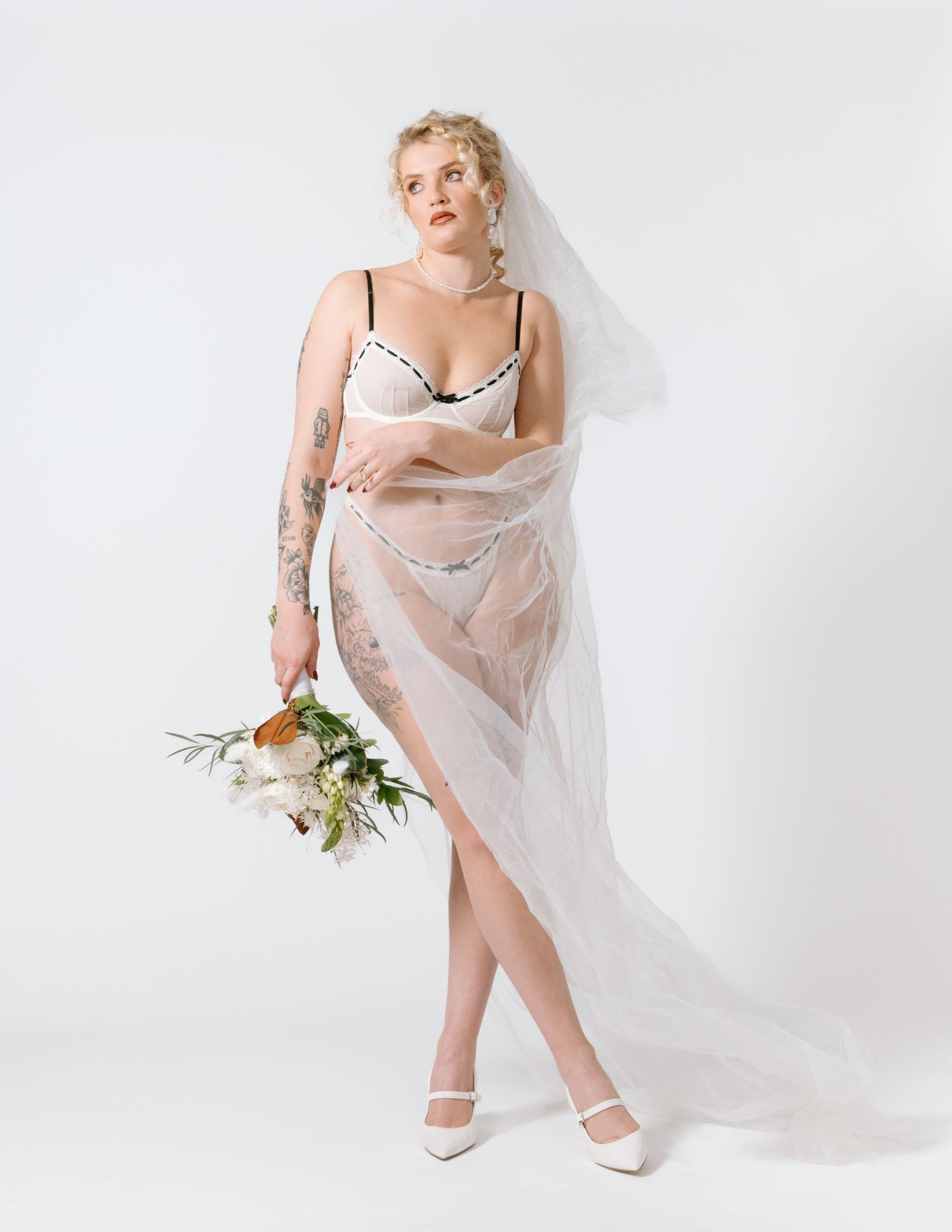 An artistic bridal portrait with sheer drapery and white flowers against a studio backdrop. Calgary Bridal Boudoir Photographer