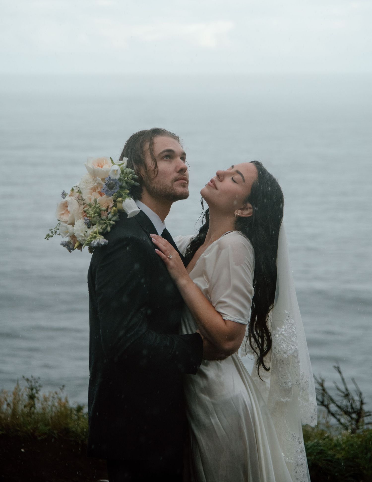 Newlyweds share intimate moments against moody ocean backdrop on their wedding day. Calgary Wedding Photographer
