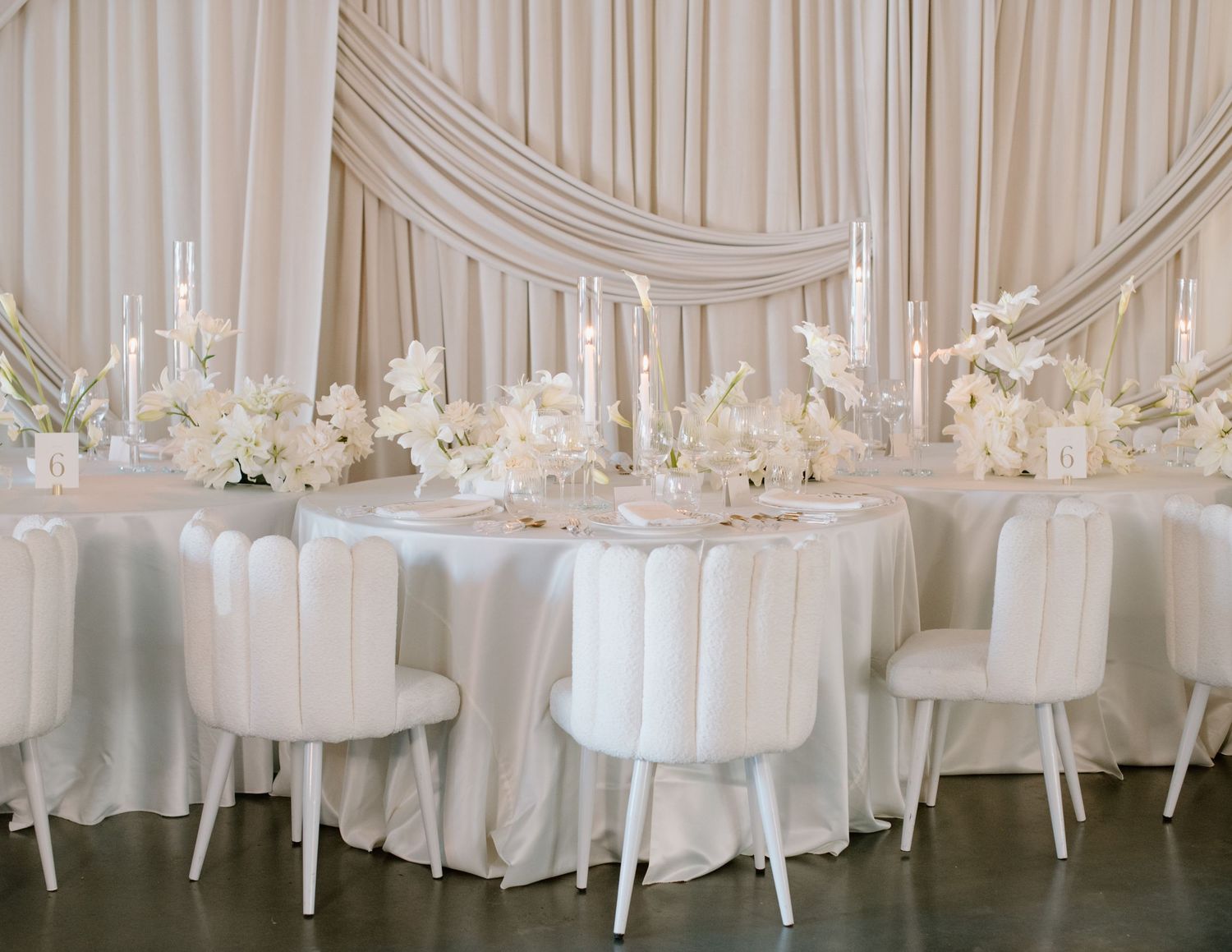 White draped wedding reception venue with elegant table settings and chandeliers at The Brownstone Venue, Calgary. Calgary Photographer.