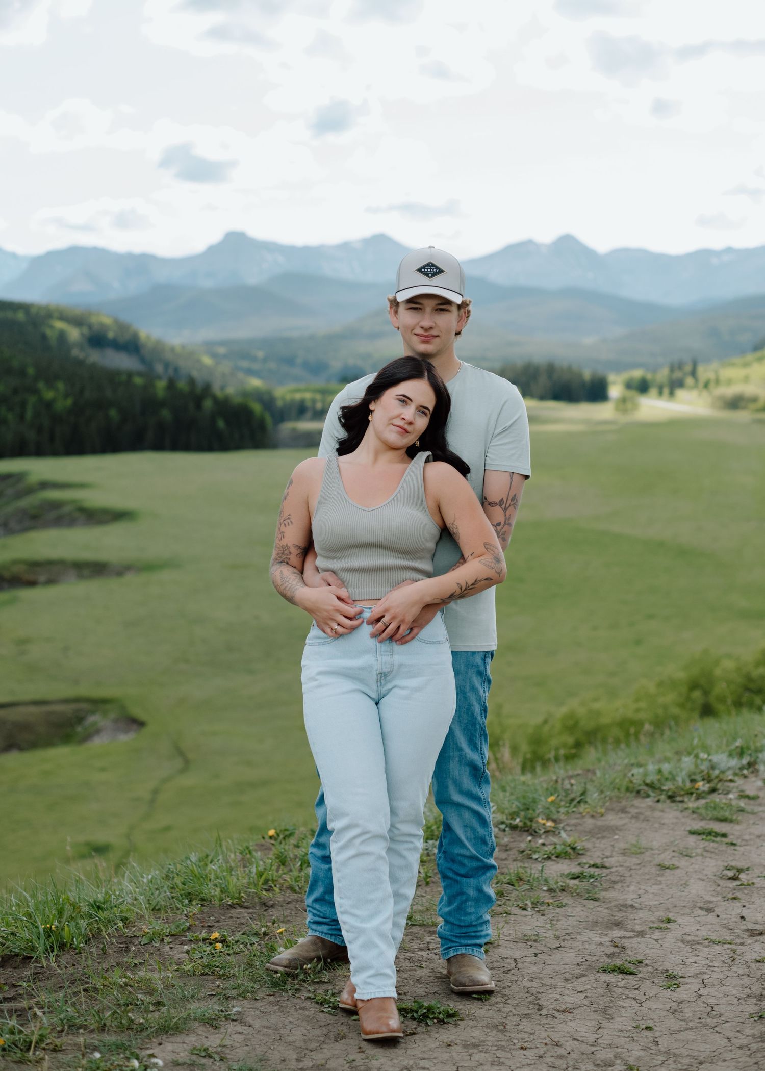 A couple embracing on a mountain trail with scenic valley views. Calgary Alberta Engagement Photographer.