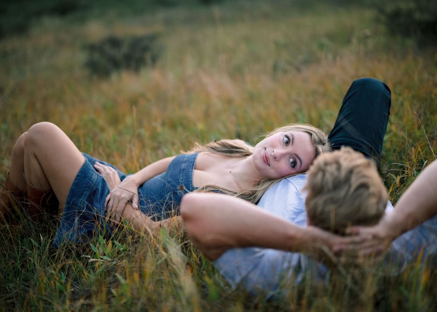 A cinematic sequence showing a person lying down in tall grass at golden hour with artistic lighting.