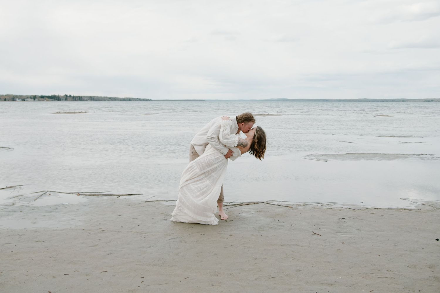 A romantic beach photoshoot showing an intimate moment between a couple near the ocean. Calgary Alberta Maternity Photographer.