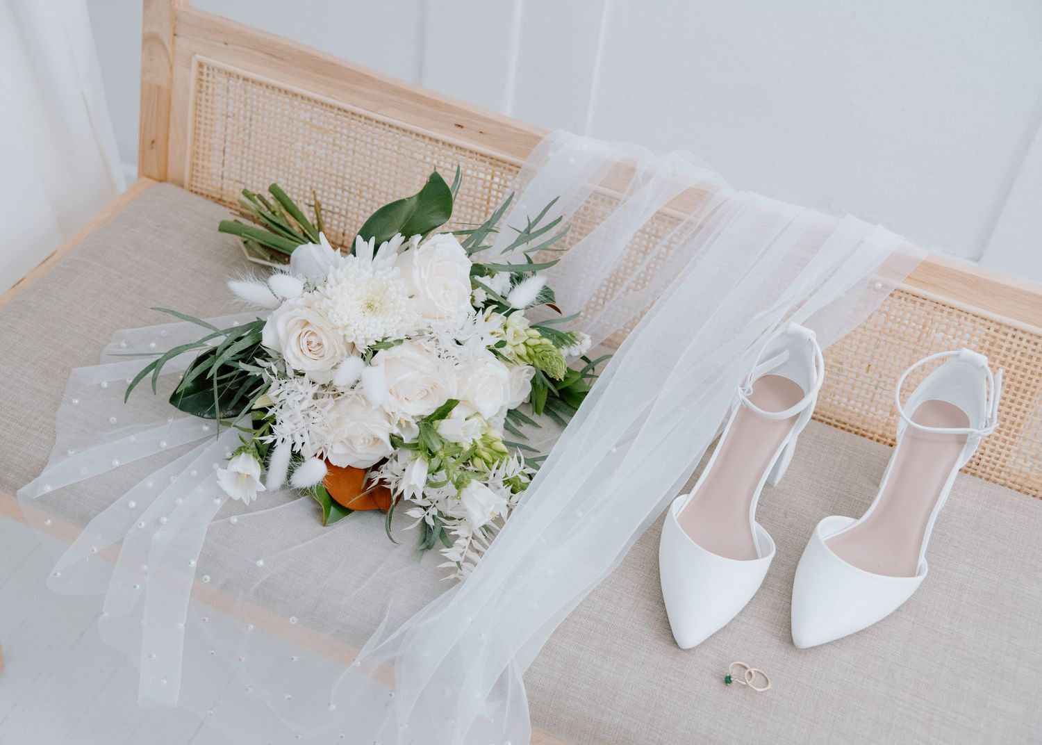 Elegant wedding details including white shoes, flowers and stationery arranged on a light surface at The Study Calgary Wedding Photographer