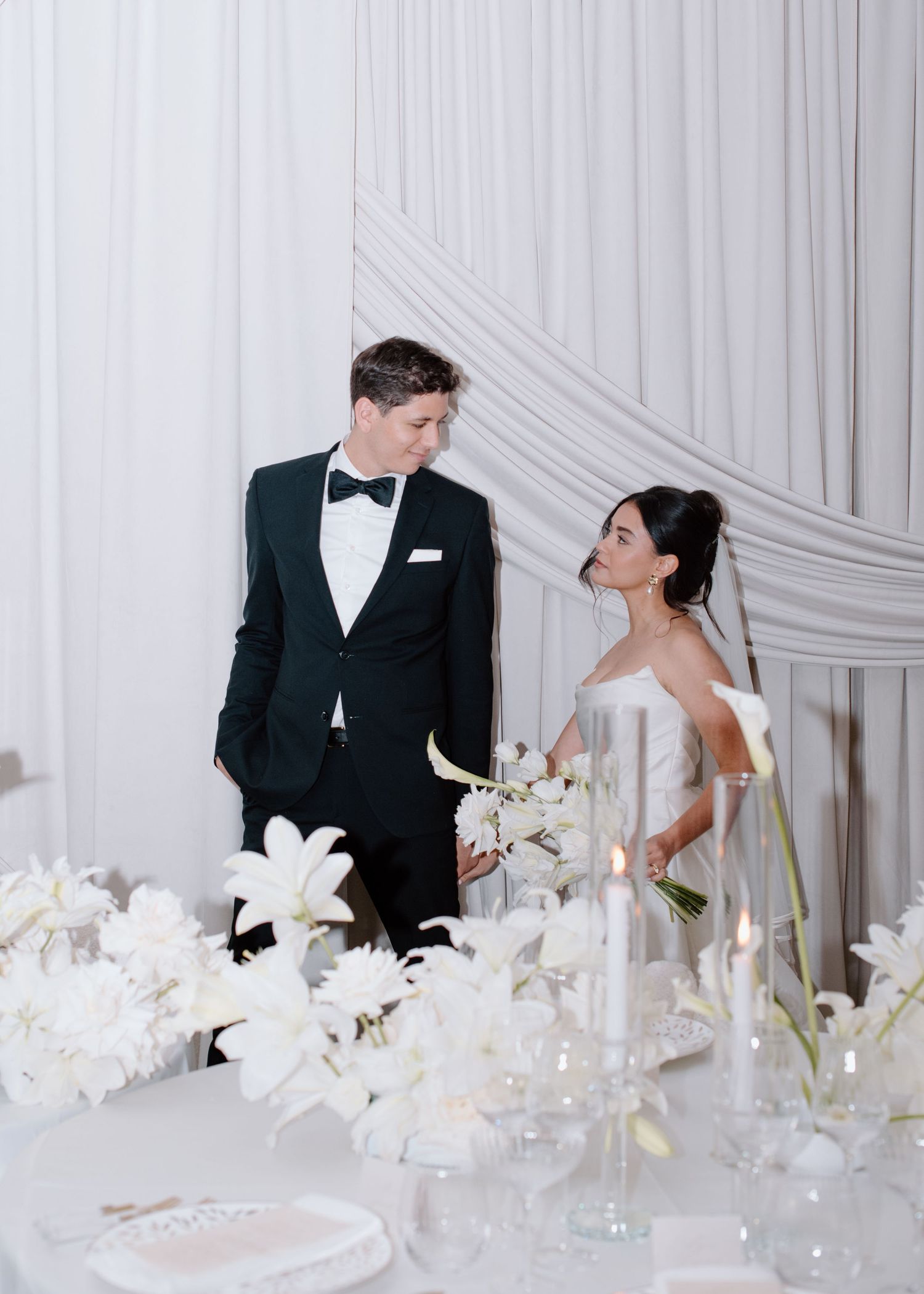 Wedding couple shares playful moments among white floral decorations in elegant setting at the Brownstone YYC. Calgary Wedding Photographer