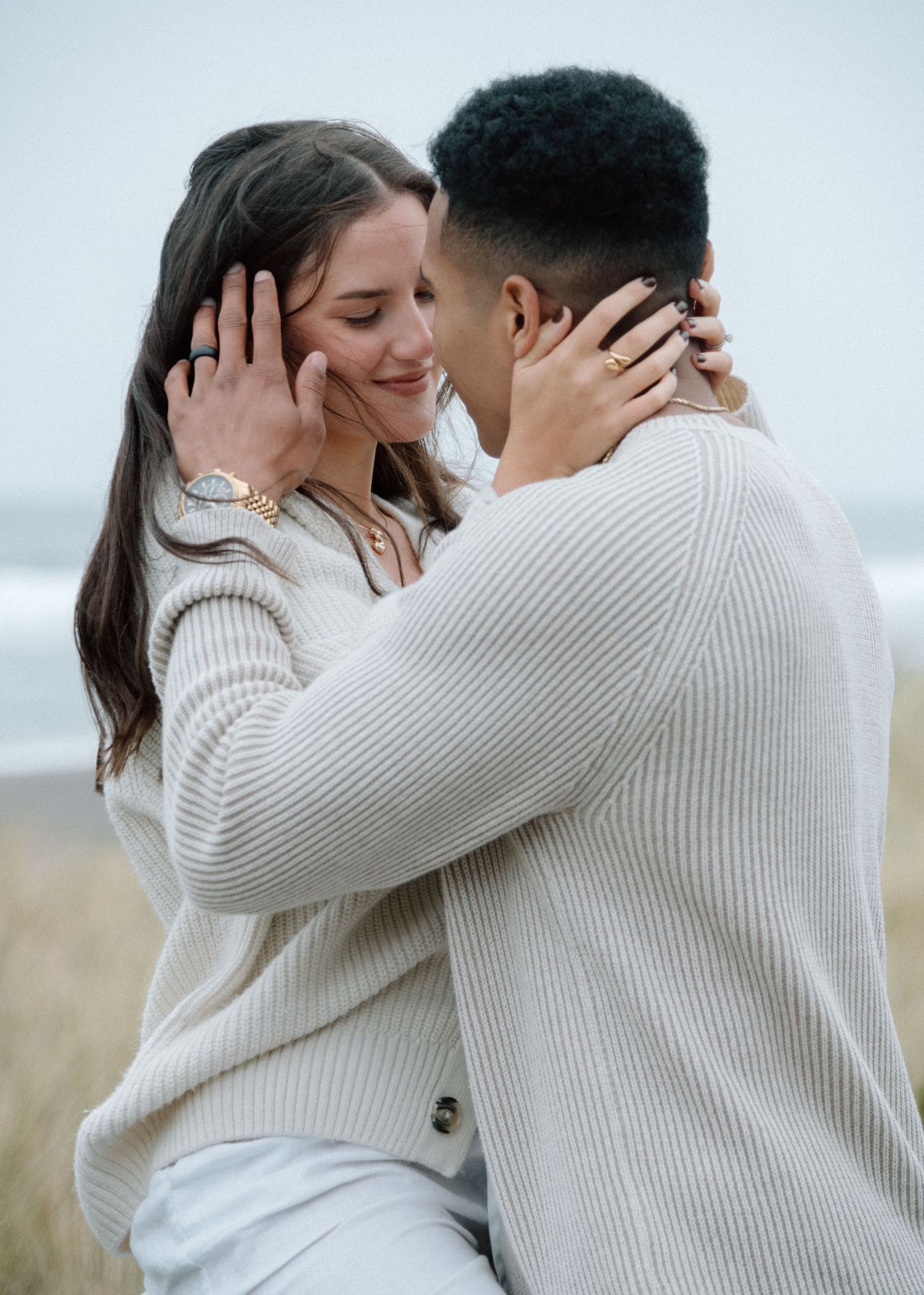 Couple in white sweaters sharing intimate embraces across multiple romantic photos with a soft light background.