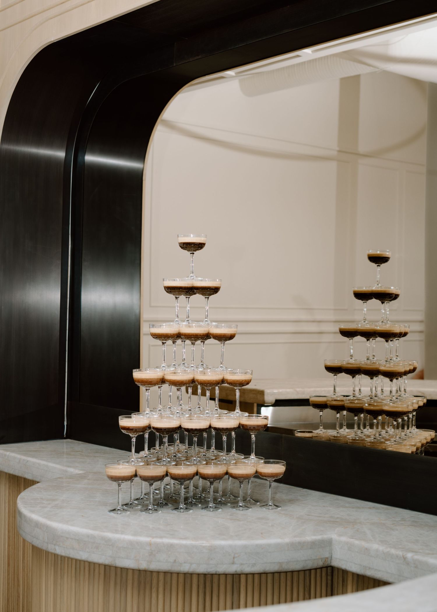 Tiered champagne tower display on marble countertop with black archway framing at the Studio at Vic Park YYC Wedding Photographer
