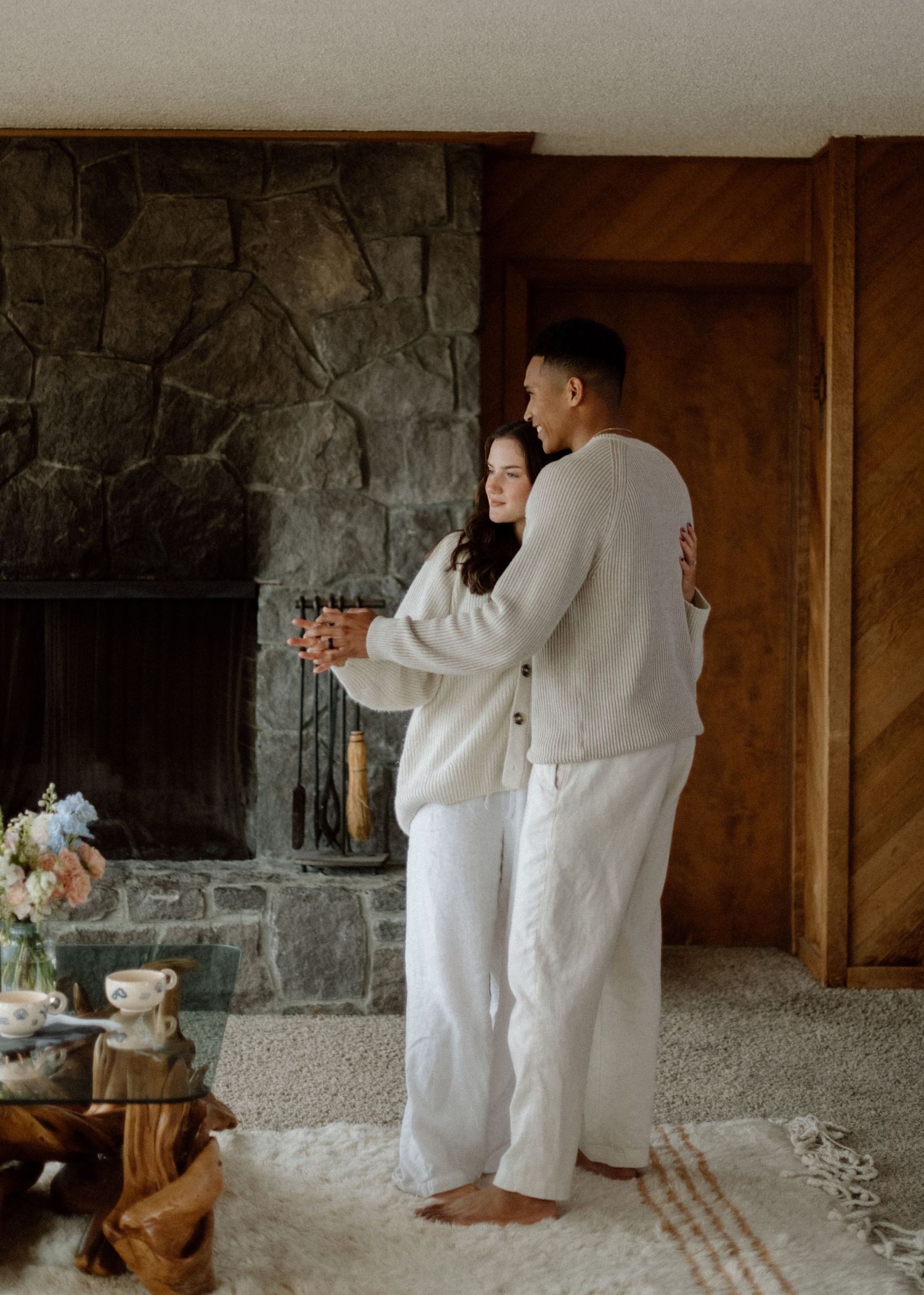 Two people in white outfits dance together in a rustic stone room with atmospheric lighting.