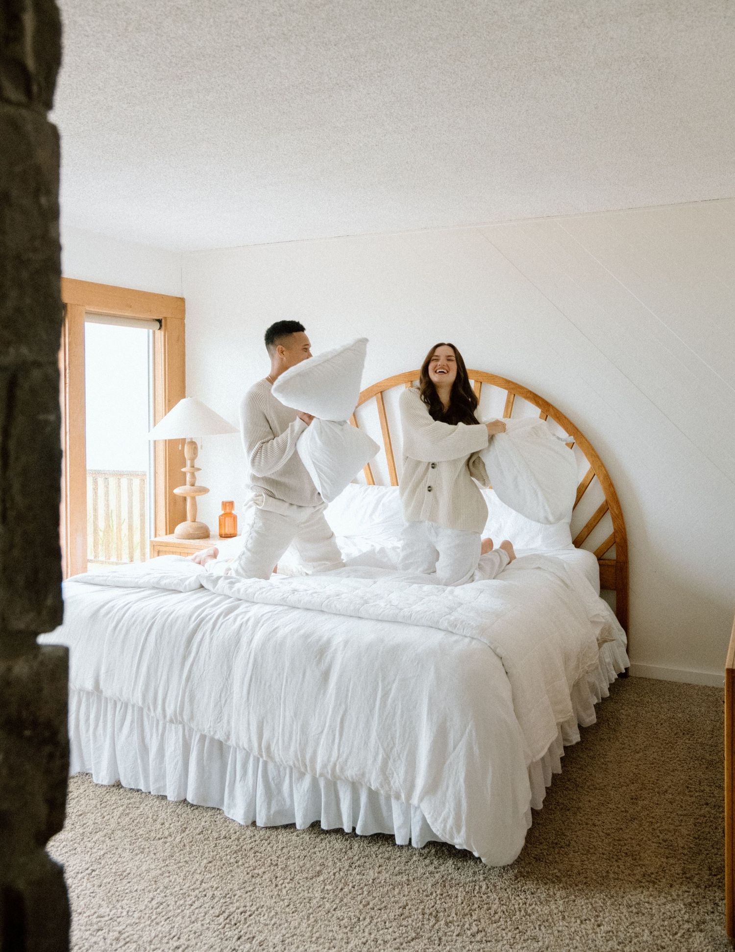 A white ruffled bedspread with several swan shaped towel animals arranged decoratively on a queen sized bed.