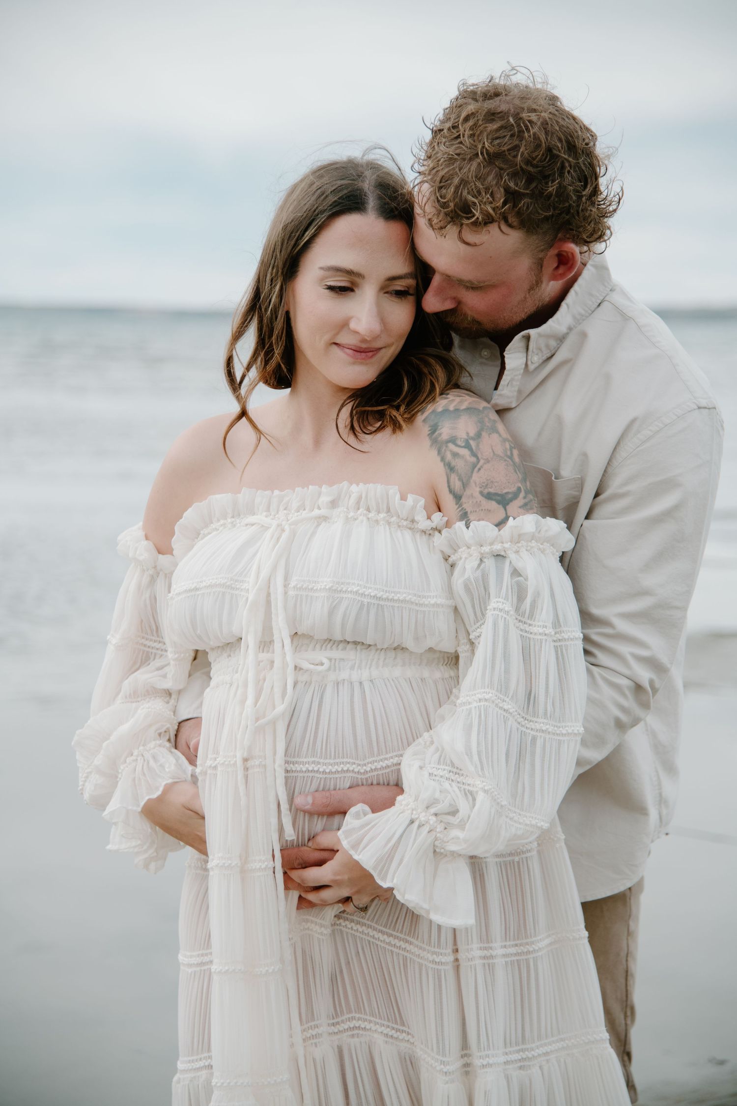 An intimate beachside portrait featuring a vintage white dress and soft, muted tones. Calgary Alberta Maternity Photographer.