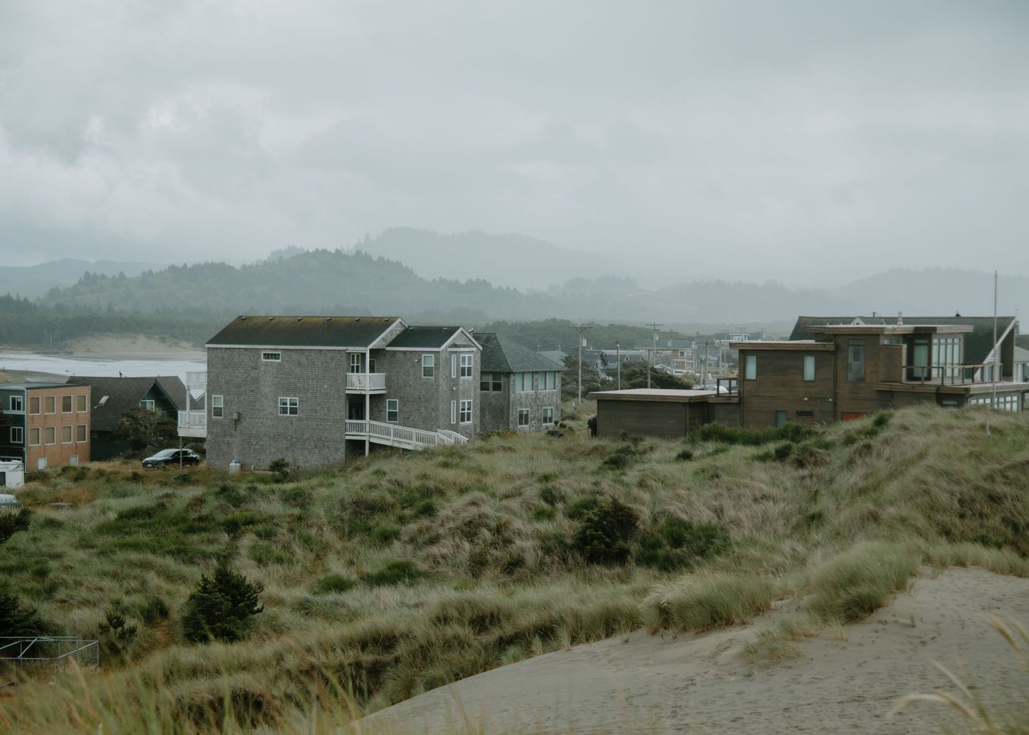 Coastal homes built along sandy dunes with mountains visible in the misty distance on Oregon Coast. Calgary Lifestyle and Engagement.