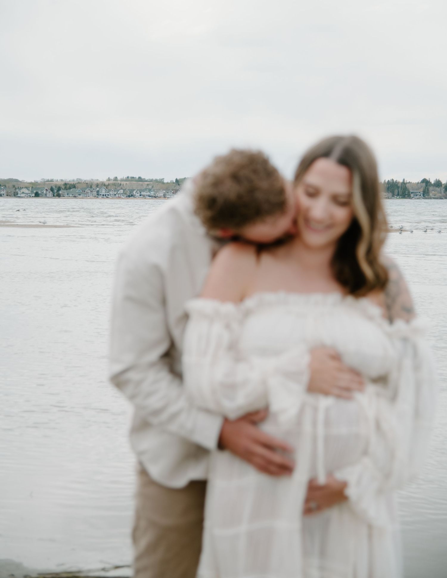 Intimate pregnancy photography capturing tender moments between a couple on a misty beach. Calgary Alberta Maternity Photographer.