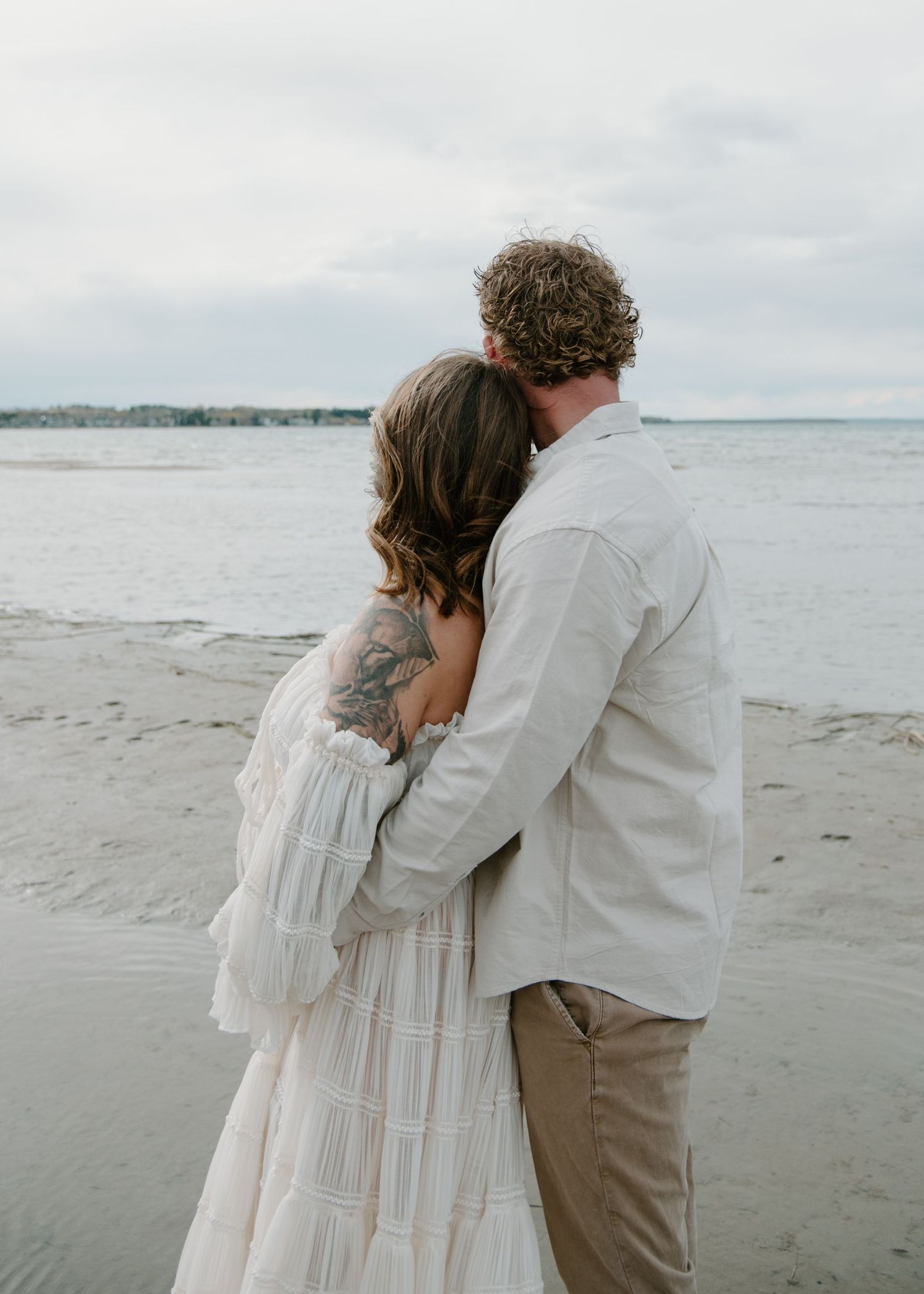 Intimate beachside embrace between a couple during sunset maternity photoshoot. Calgary Alberta Maternity Photographer.