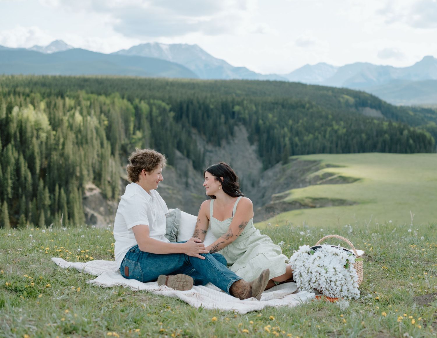 A romantic picnic scene on a blanket with stunning mountain vistas. Calgary Alberta Engagement Photographer.