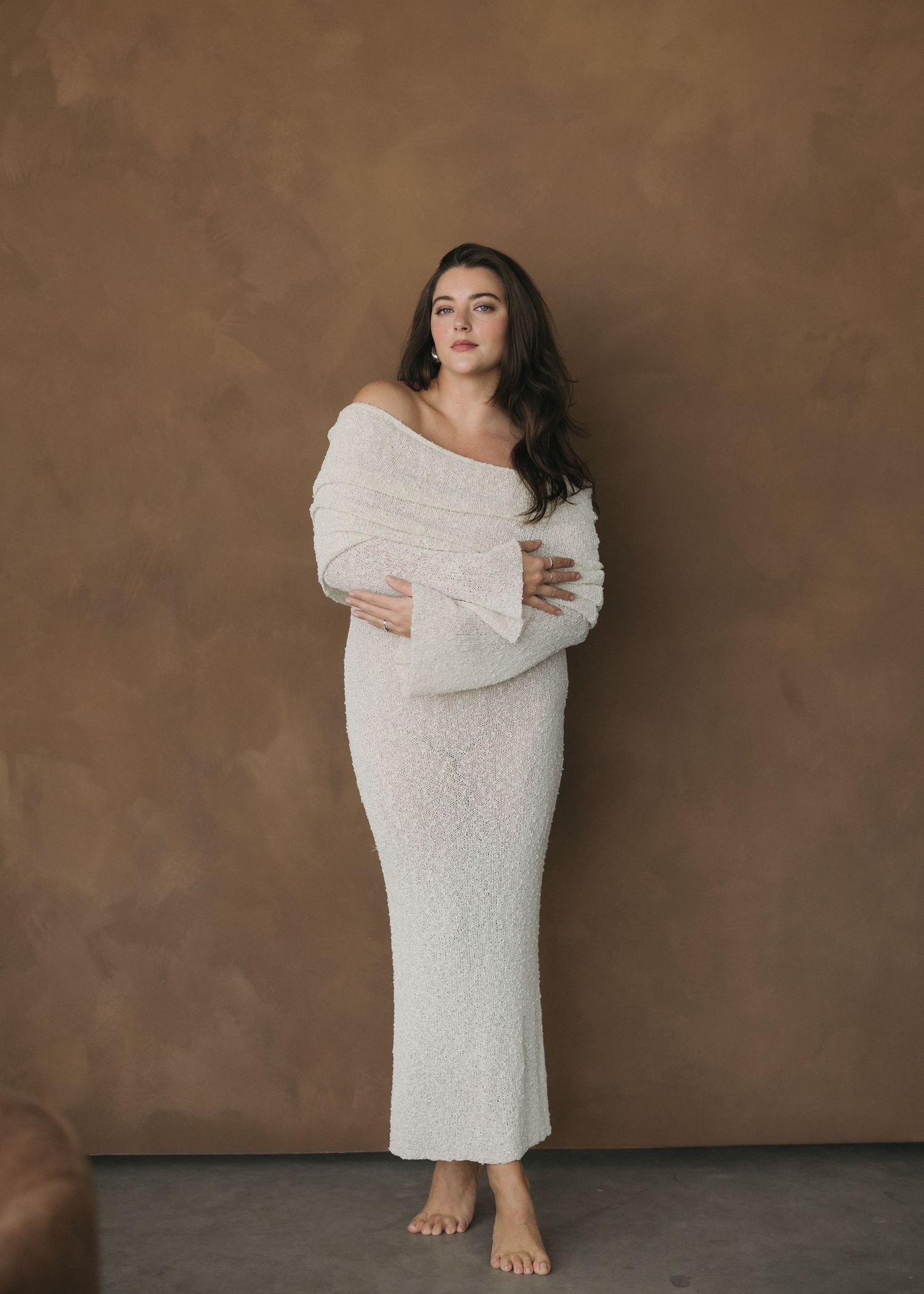 A series of artistic maternity portraits showing a woman in a white dress against a brown backdrop in various poses.