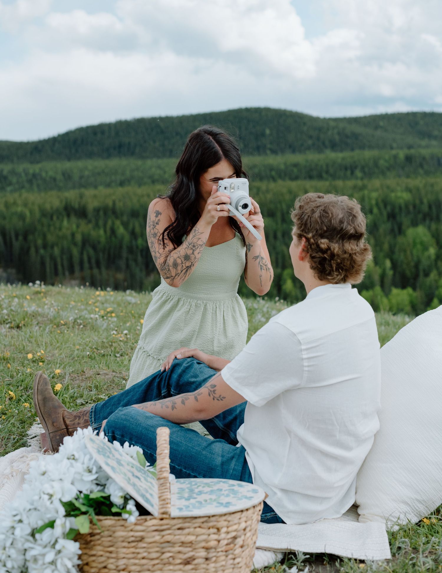 A picnic scene in the mountains with a couple looking at photographs. Calgary Alberta Engagement Photographer.