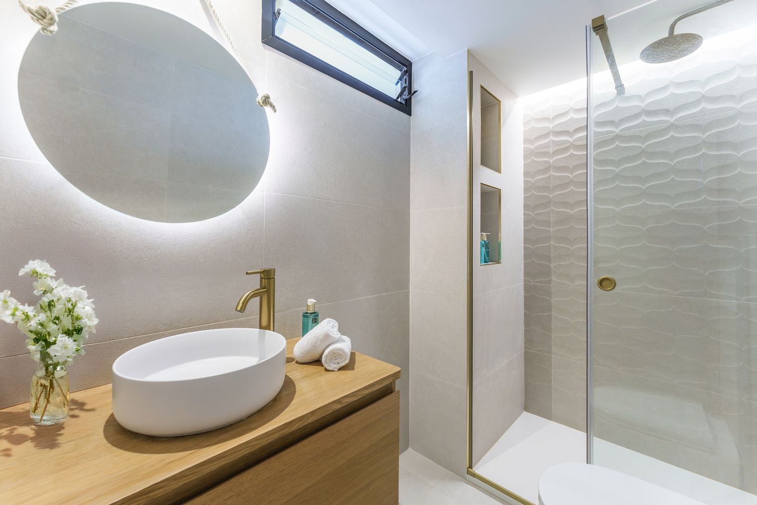 Stylish bathroom in Santa Pola, Elche, featuring warm wood accents and backlit mirror. Captured for short-term rental and property listing.