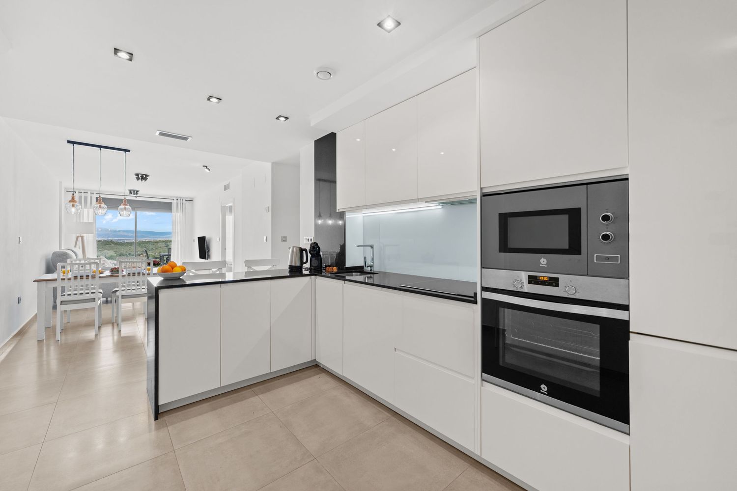 Sleek open-plan kitchen and dining area with a sea view in Gran Alacant , Spain. For Airbnb rental photography.