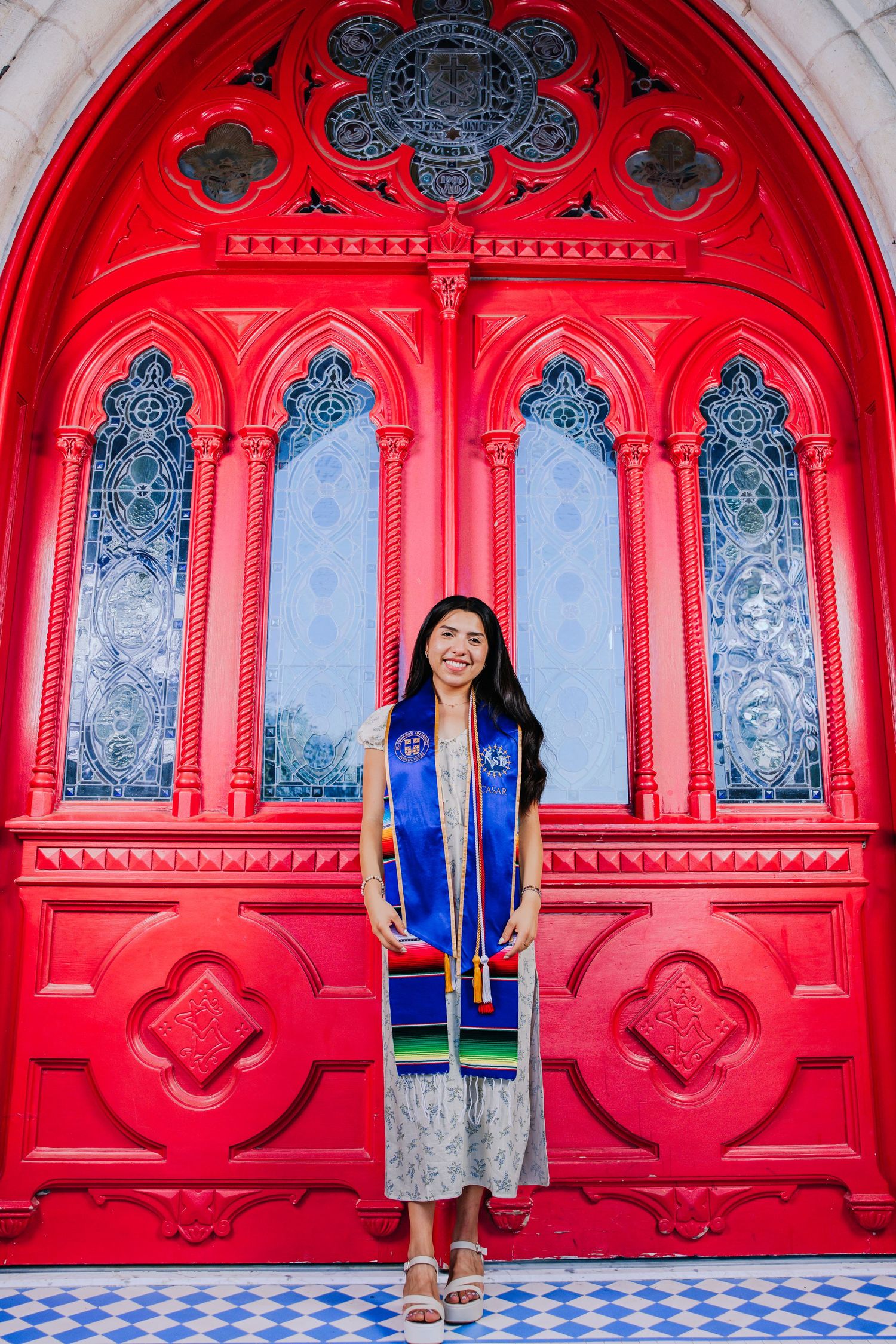 A series of four red ornate archways with gothic details and blue windows creating a striking architectural pattern.
