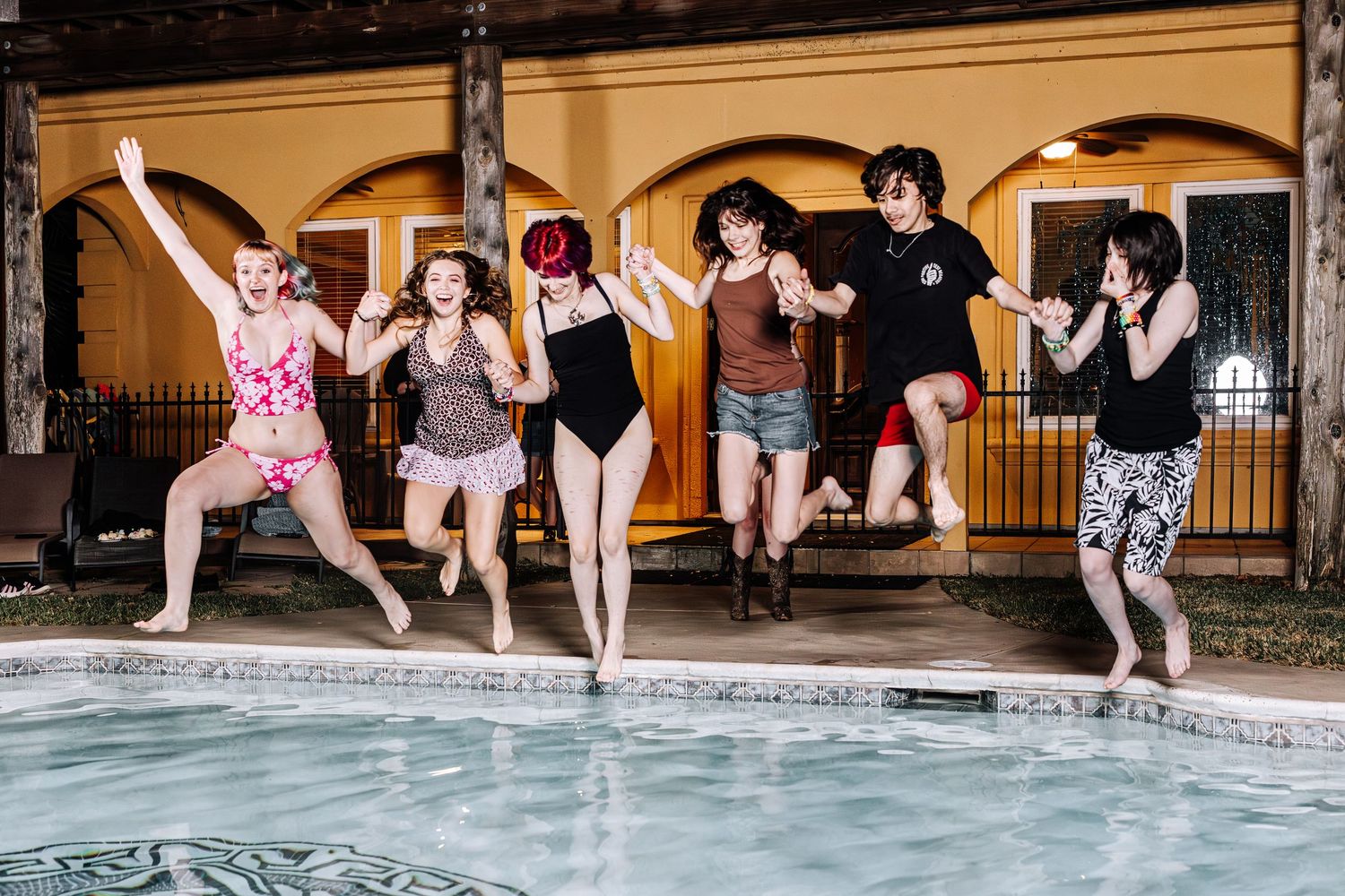 A sequence of photos showing people jumping into a pool in a synchronized motion at an outdoor venue.