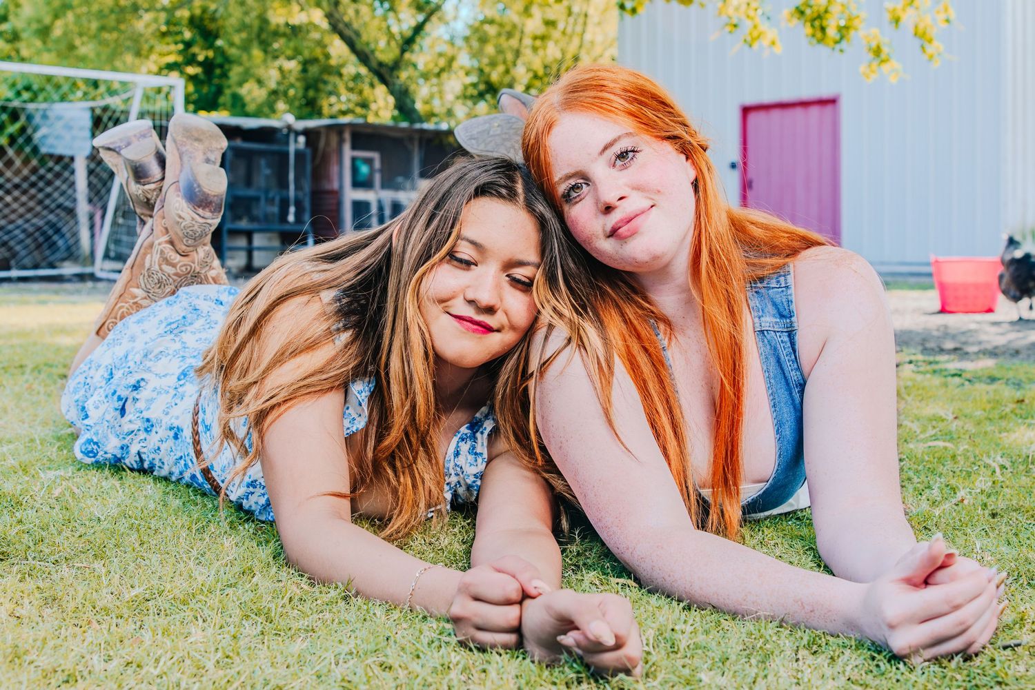 Friends relaxing together on grass during outdoor photoshoot.